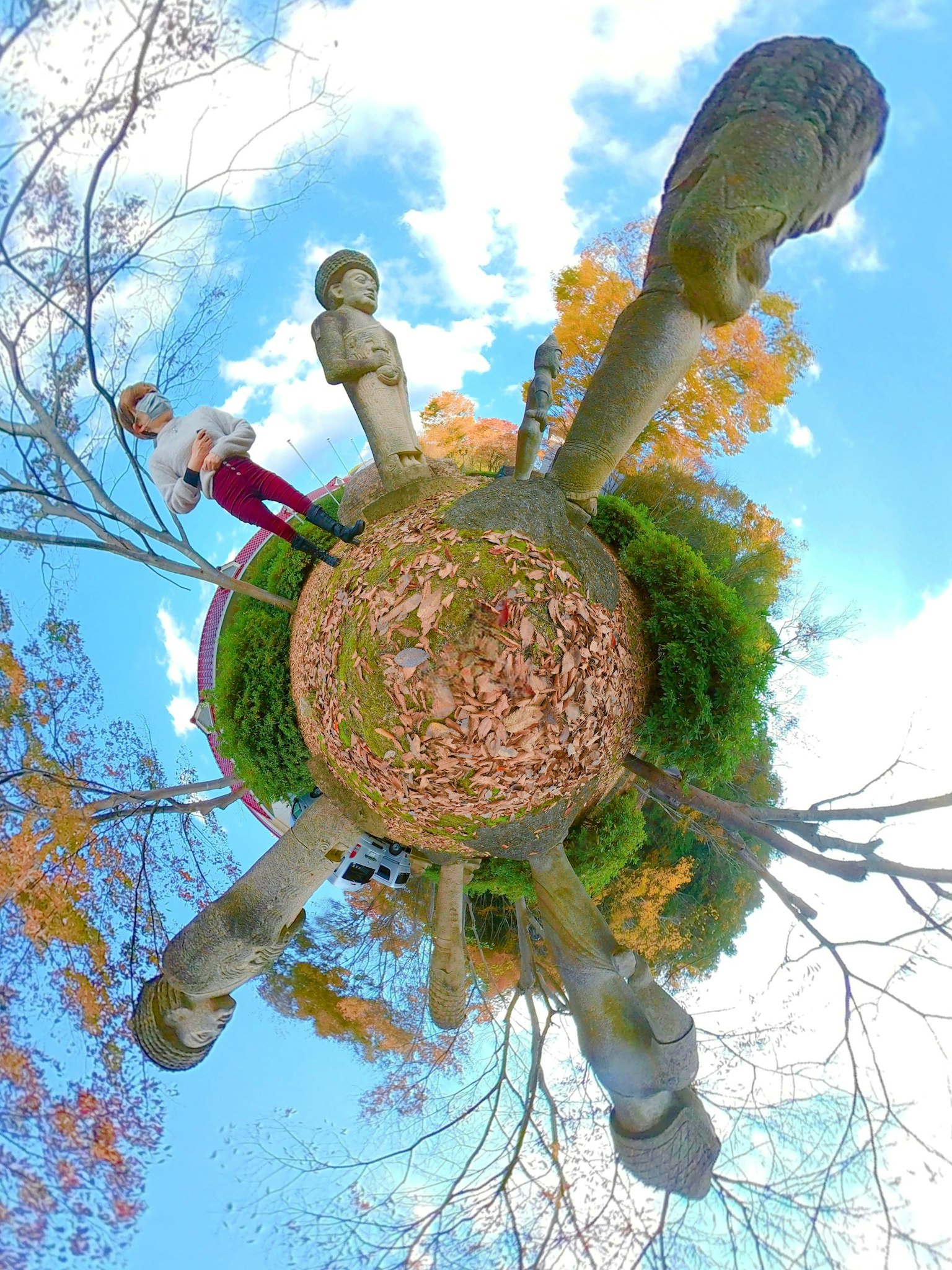 Panorama de 360 grados de una escultura y una persona en un paisaje otoñal