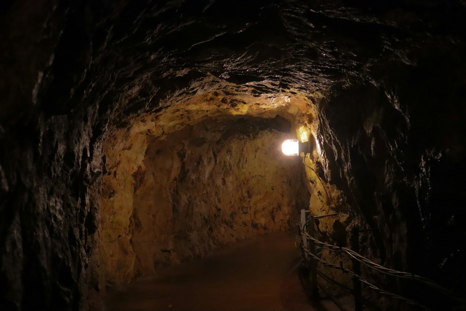 Interior of a dark tunnel with rocky walls and lighting