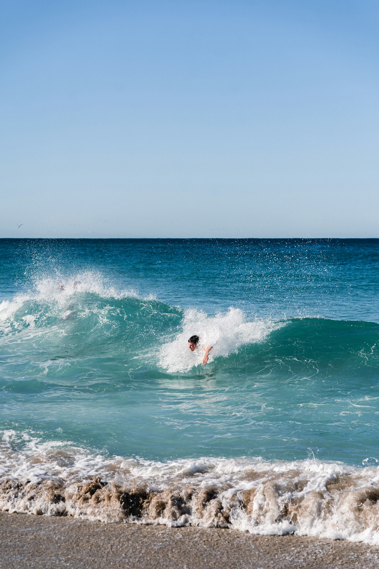Người lướt sóng trong những con sóng màu ngọc lam tại bãi biển