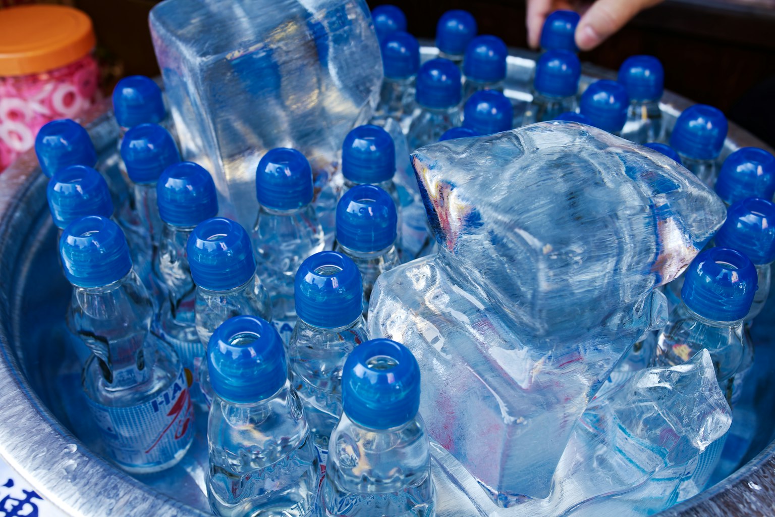 Blaue Kappen-Wasserflaschen umgeben von Eiswürfeln