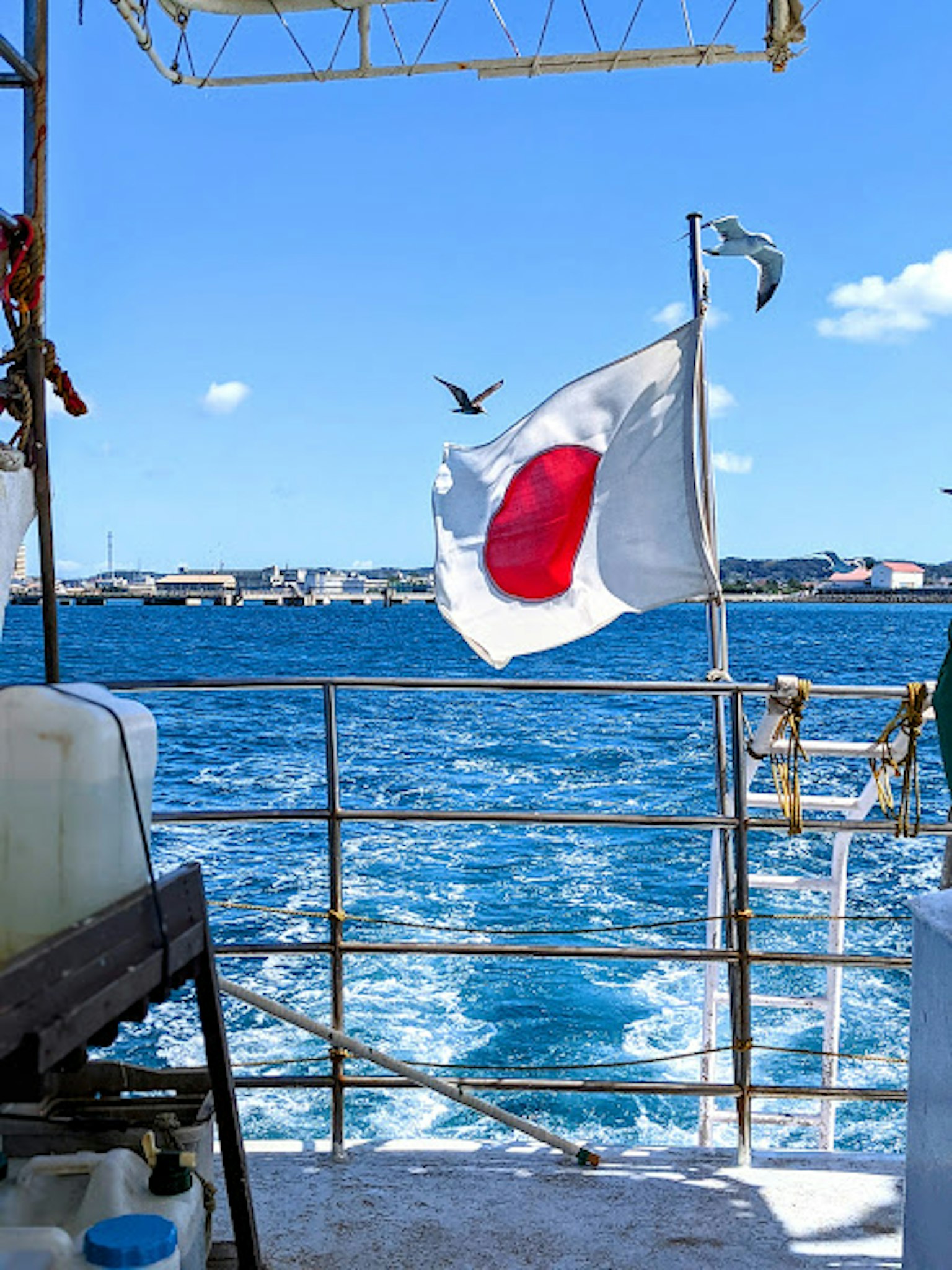 Dek sebuah kapal dengan laut biru dan bendera Jepang