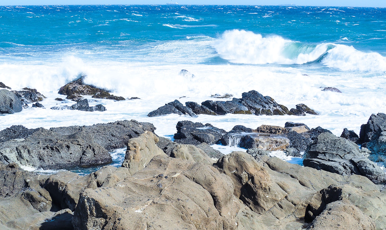 Blue ocean waves crashing against rocky shore