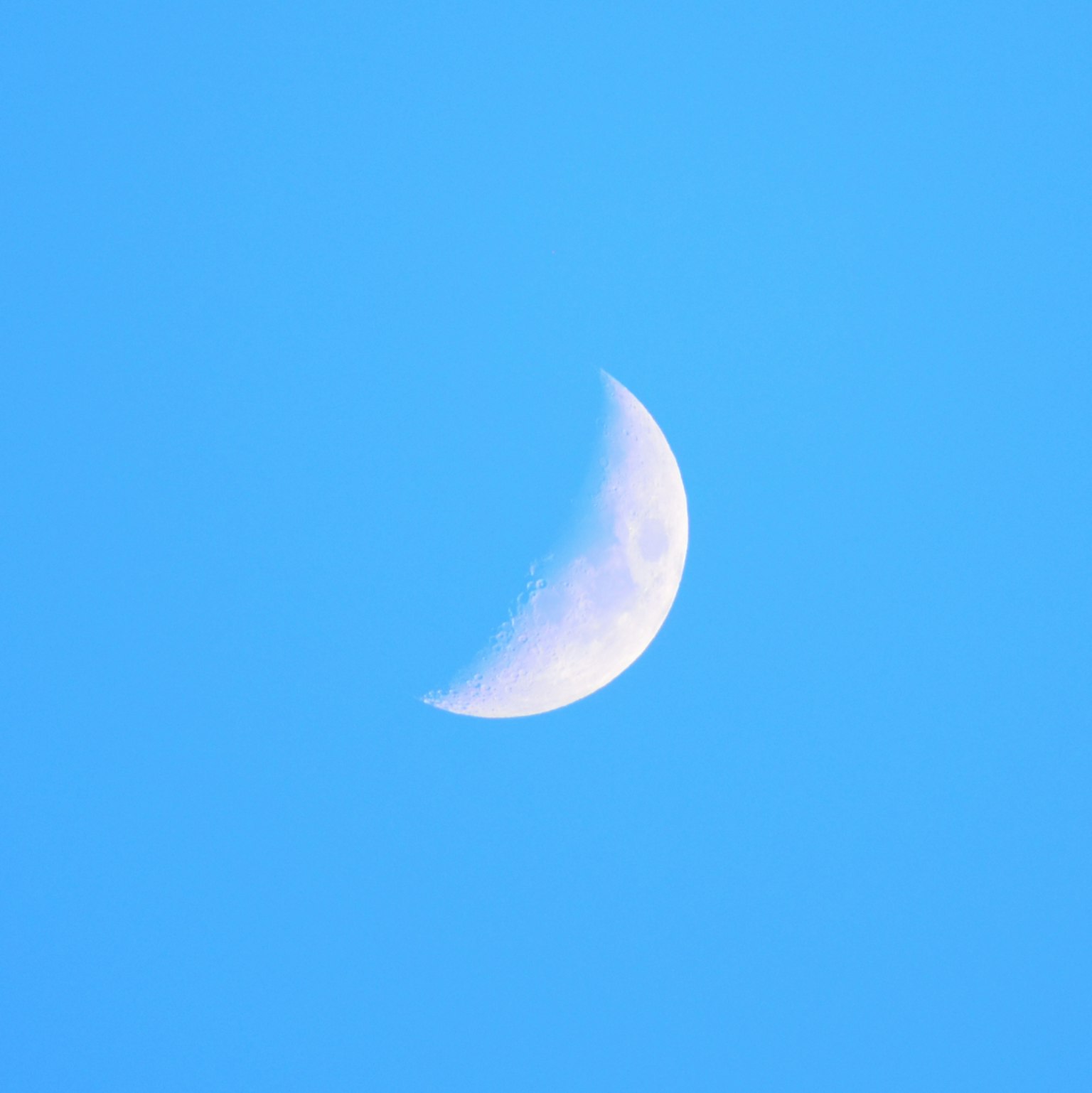 Lune croissante brillante contre un ciel bleu