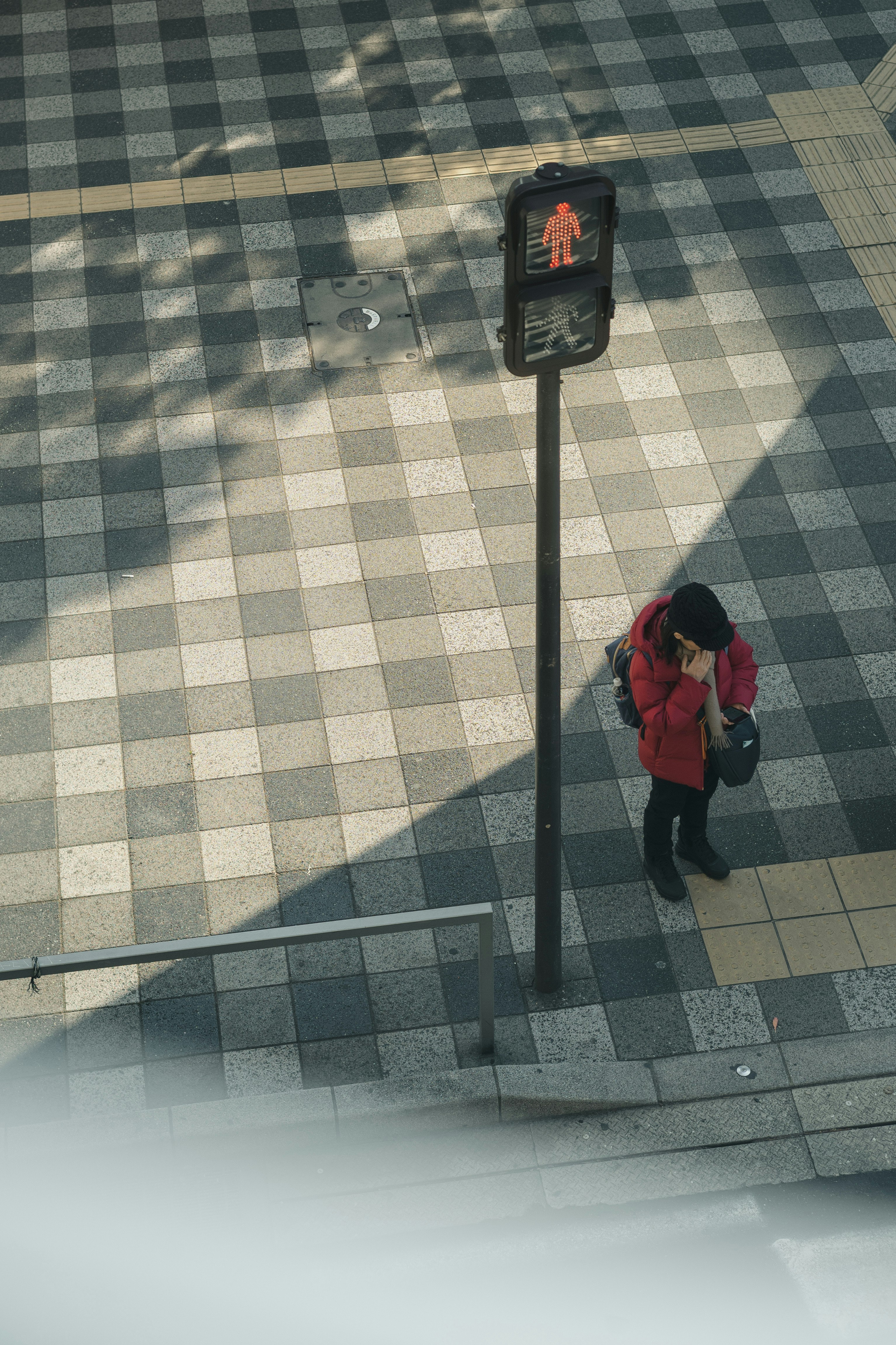 福冈市博多区斑马线前，穿红色外套的人抬头看行人信号