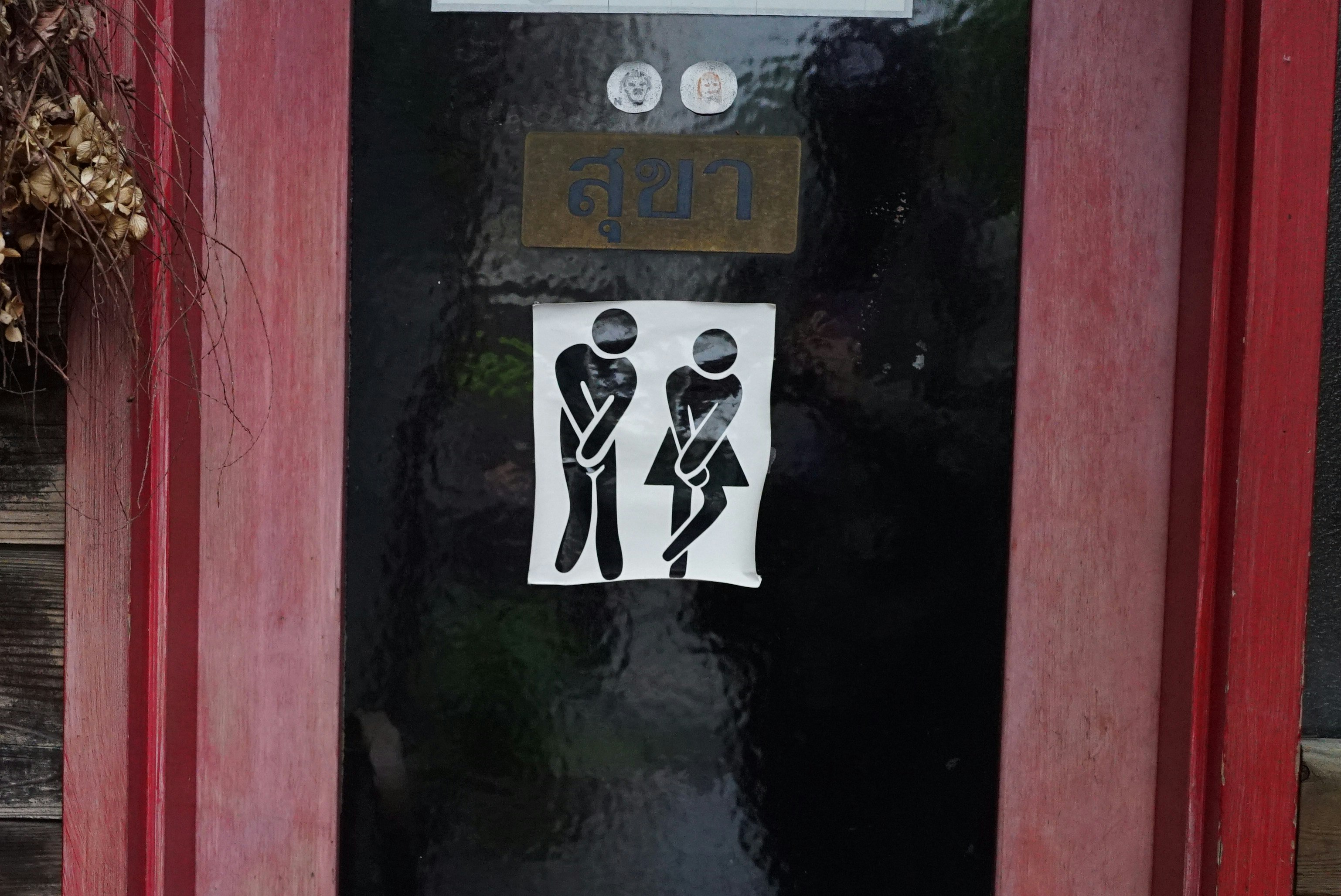 トイレの案内サインがある赤い扉の前の壁