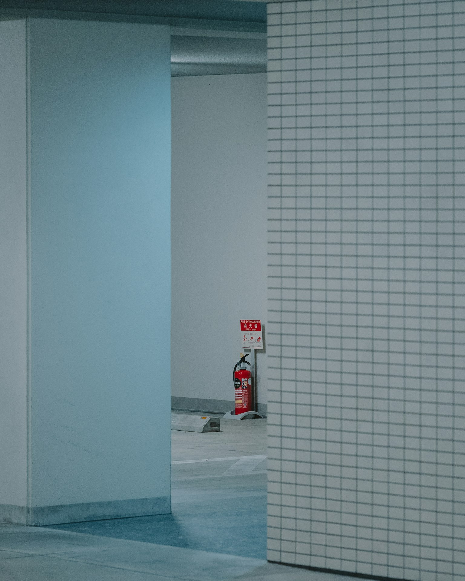 蓝色调的空间,白色瓷砖墙和可见的灭火器
