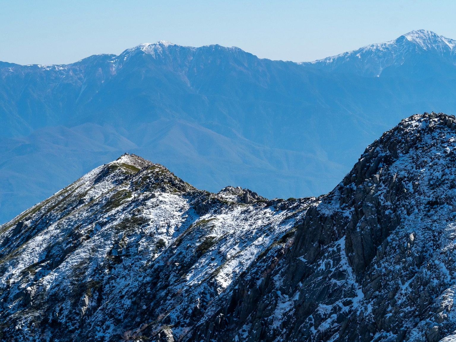 Paisaje montañoso cubierto de nieve con cielo azul claro