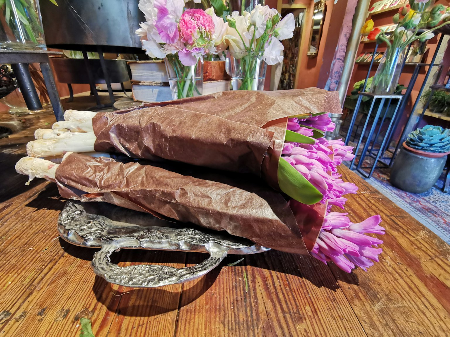 Bouquet di tulipani viola avvolti in carta marrone posati su un tavolo di legno
