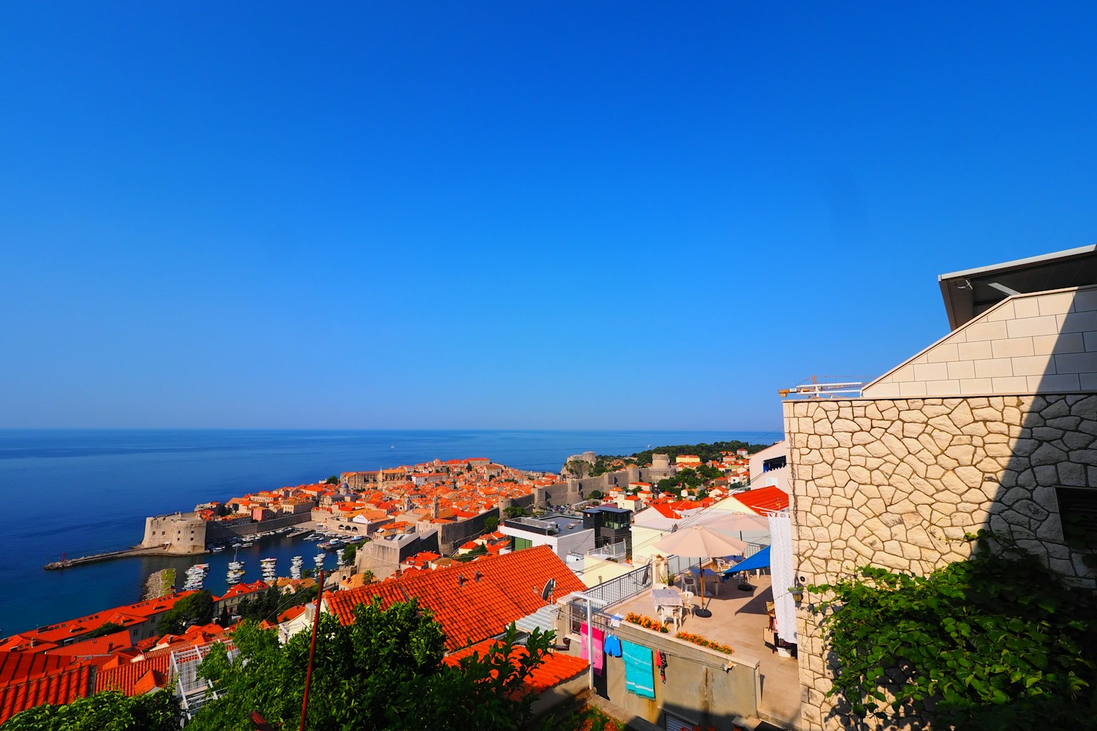 Pemandangan indah Dubrovnik dengan atap merah dan bangunan batu di bawah langit biru yang cerah