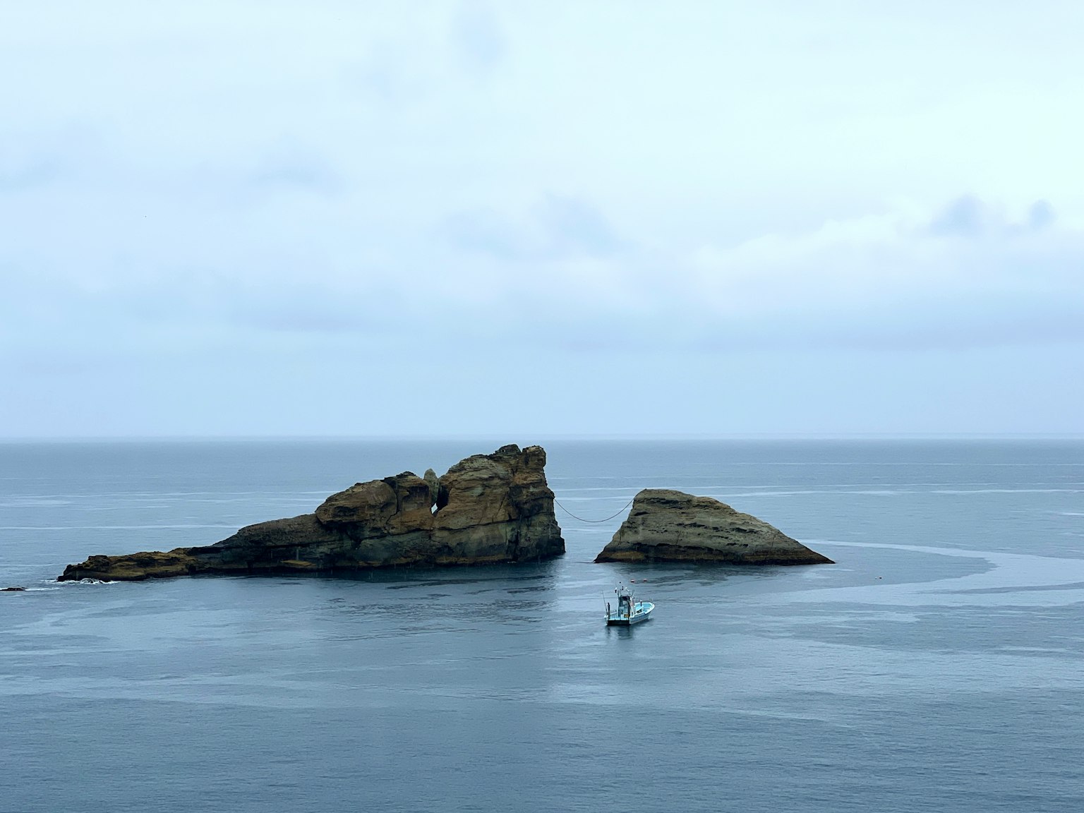 Due isole rocciose in un mare calmo con una piccola barca