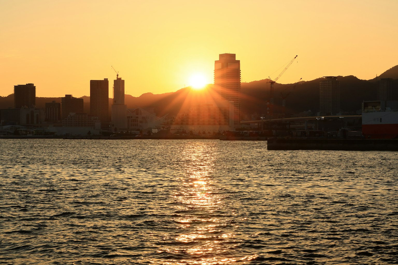 Vue de la ville au coucher du soleil avec le soleil se reflétant sur l'eau