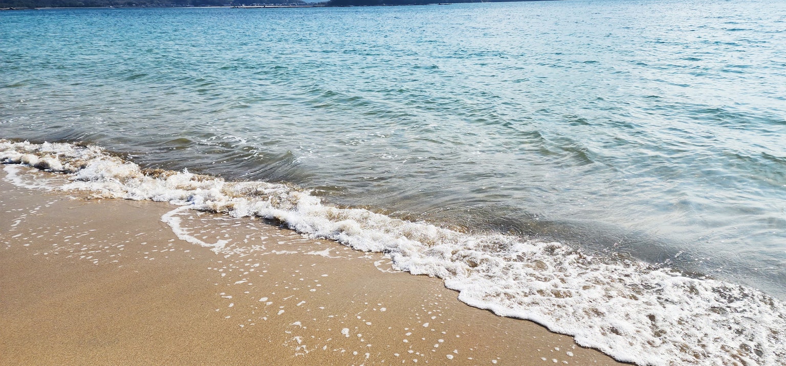 Ligne de rivage calme avec des vagues s'échouant sur la plage de sable