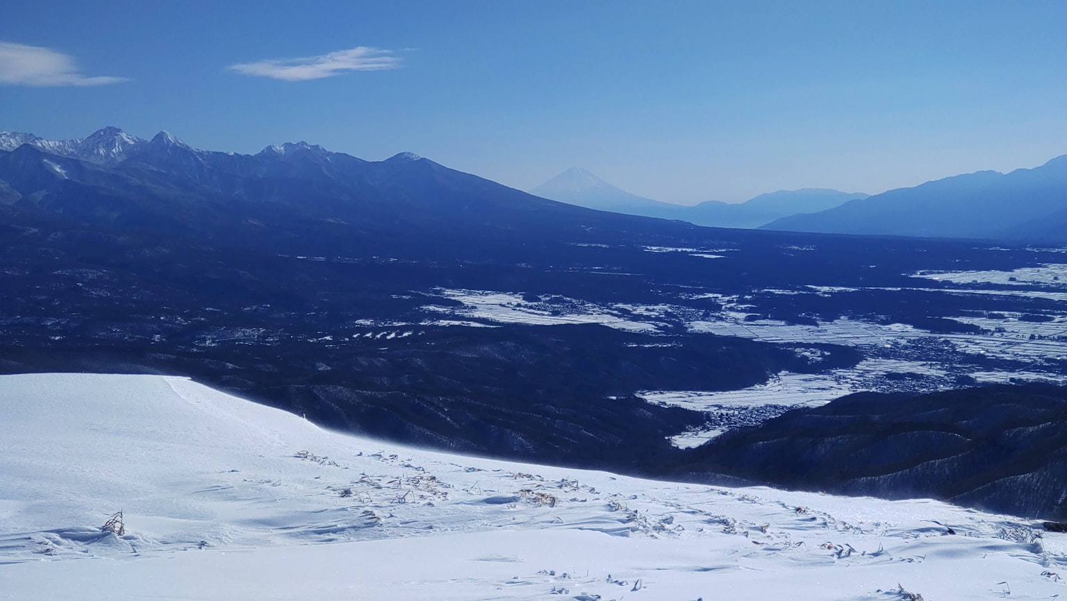 Paesaggio innevato con montagne lontane e cielo blu chiaro