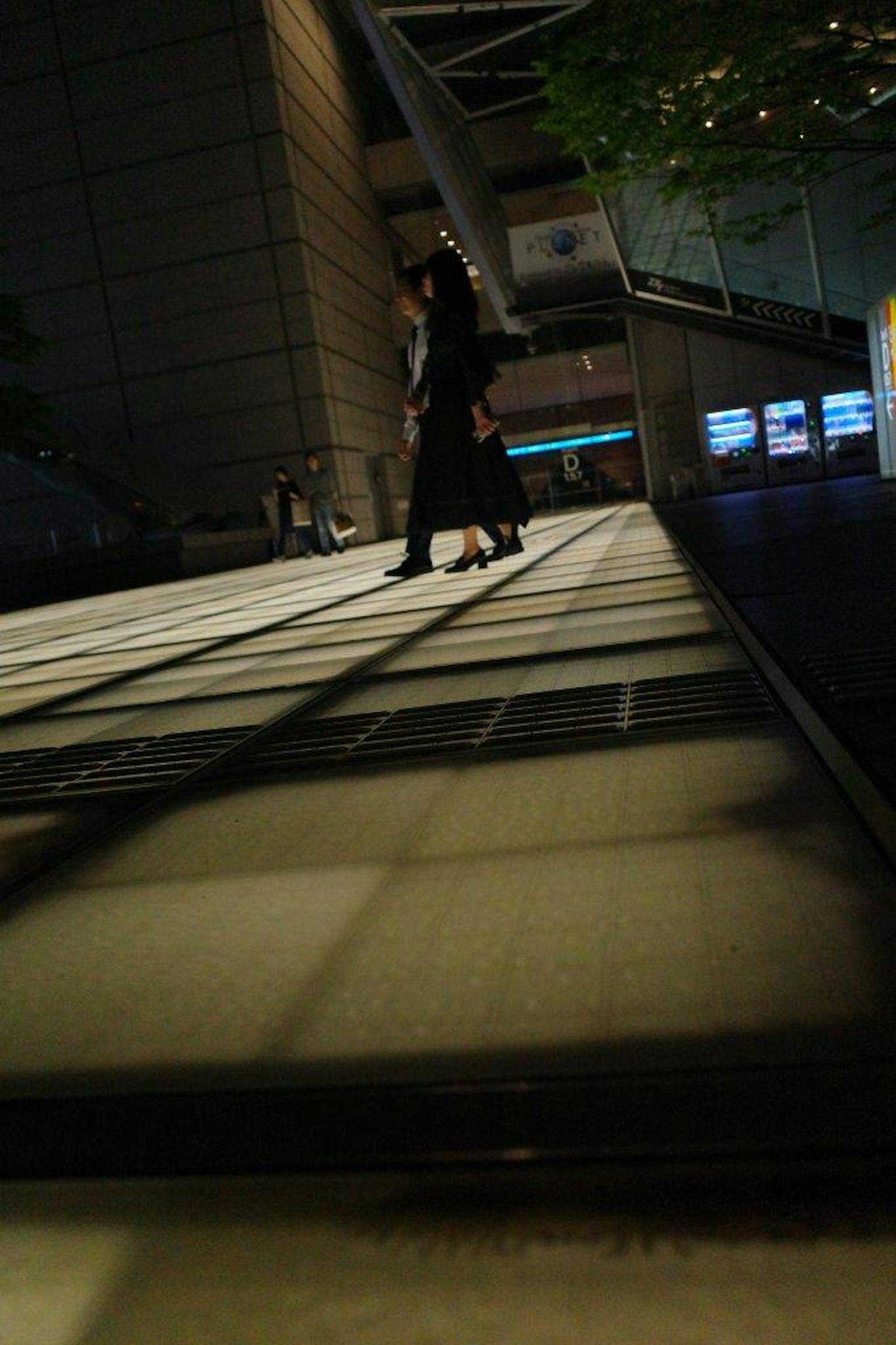 Silhouette di persone che camminano su un pavimento luminoso in un ambiente poco illuminato
