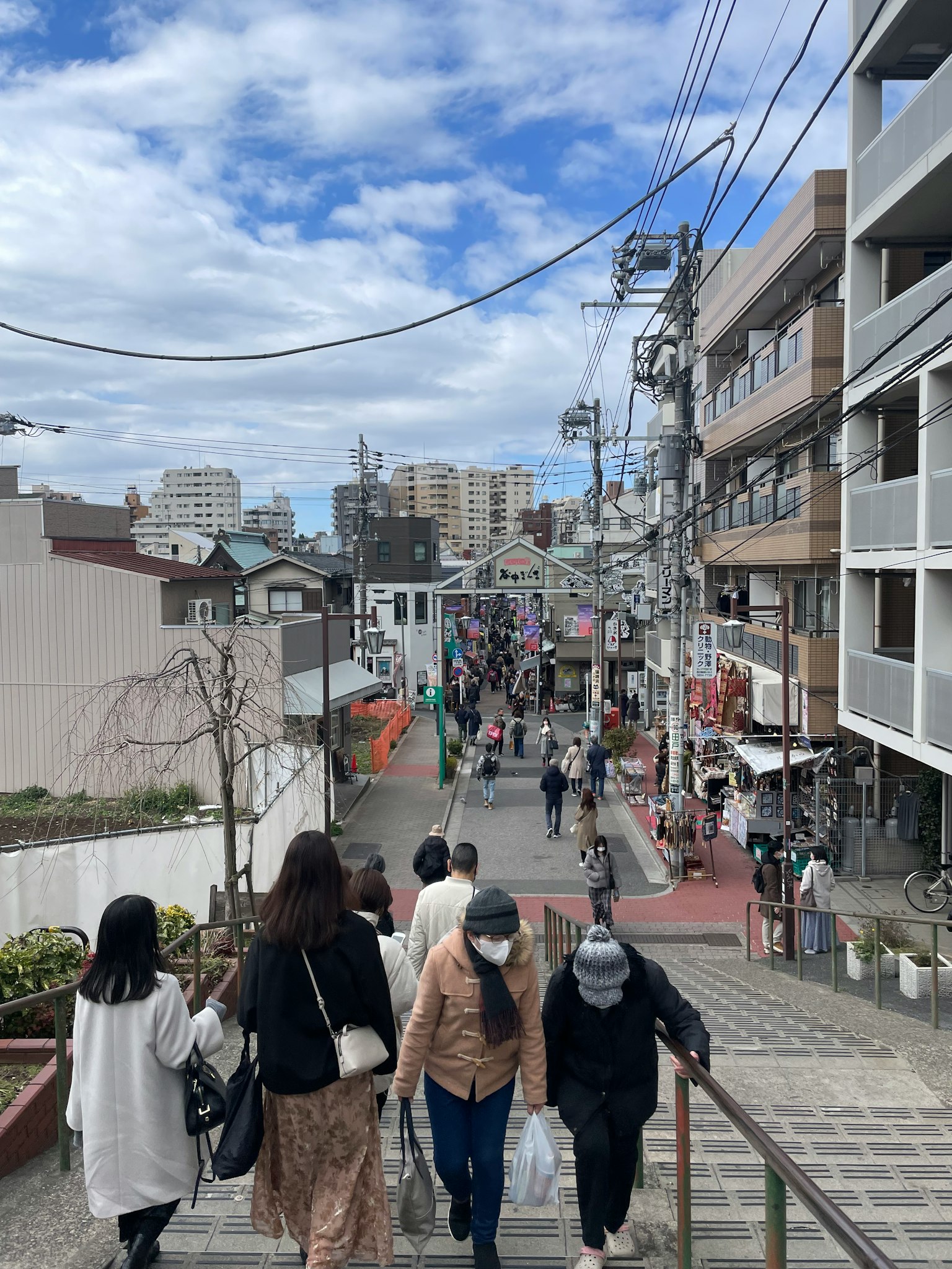 Calle concurrida con personas caminando y cielo azul