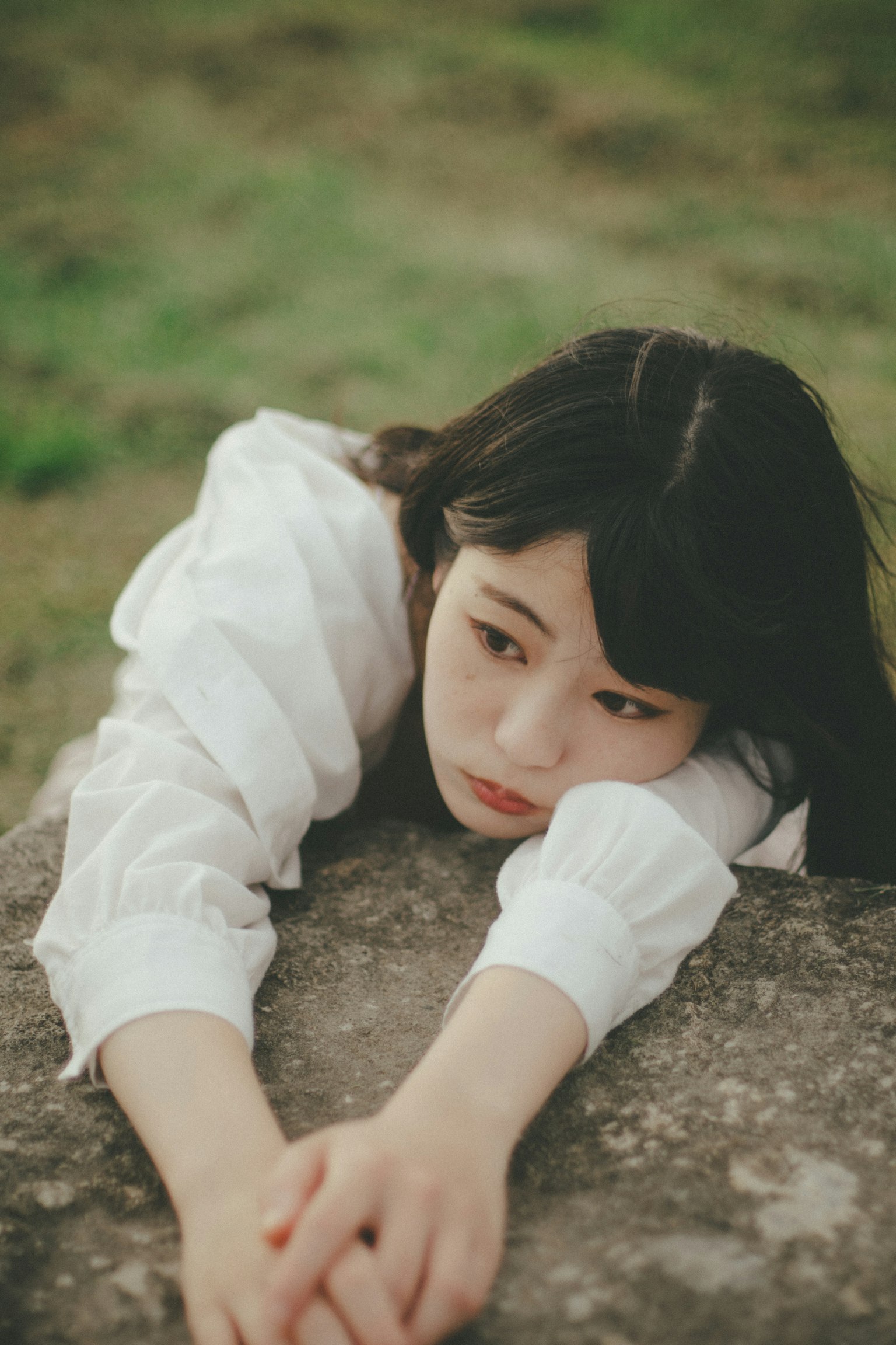 여성이 돌 위에 팔을 얹고 있는 모습과 평화로운 배경