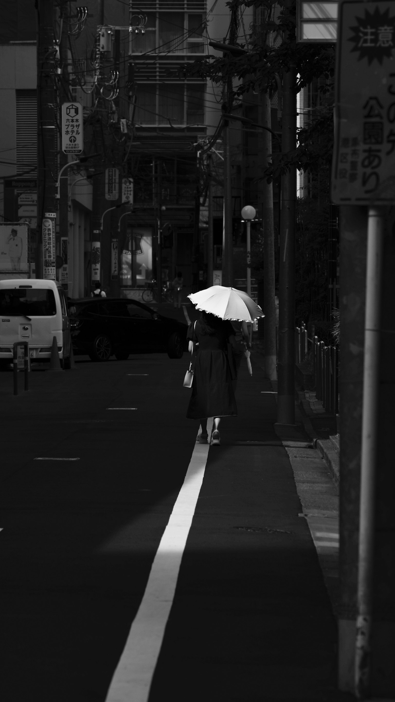 一位女性在黑暗的街道上走，手持白色雨傘