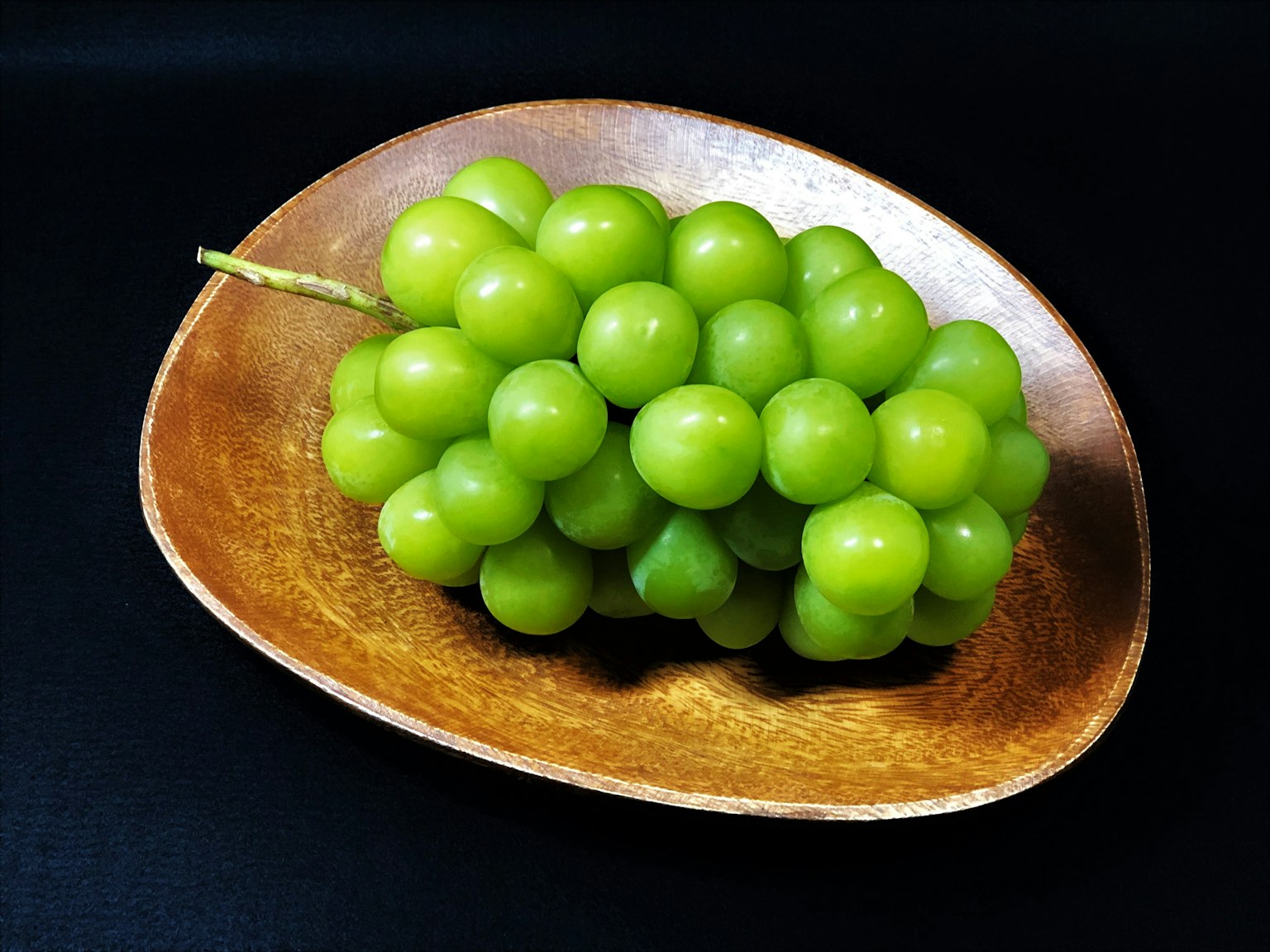 Un grappolo di uva verde fresca su un piatto di legno