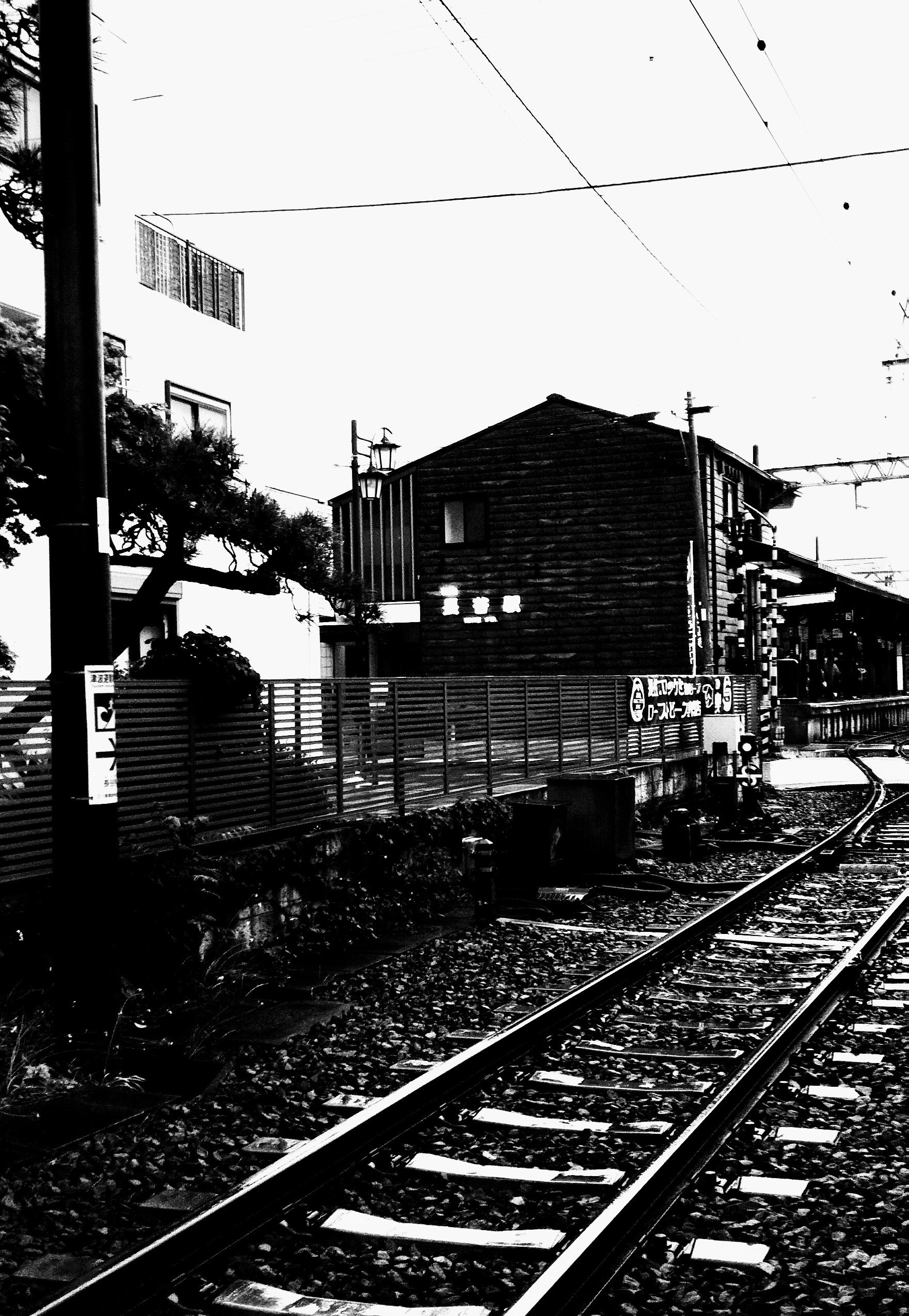 binari ferroviari in bianco e nero su un marciapiede di stazione