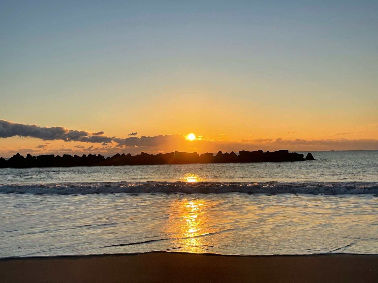 Bellissimo tramonto sull'oceano con onde e silhouette di rocce