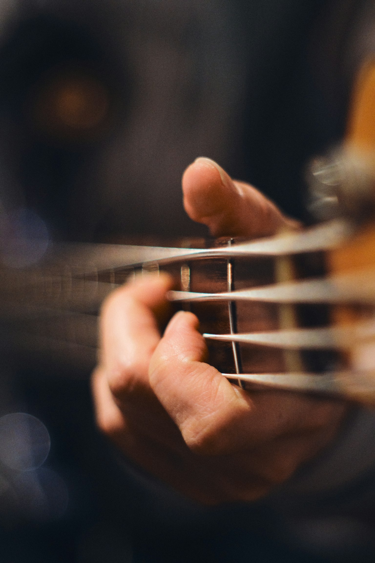 Close-up of a hand pressing strings on a bass guitar