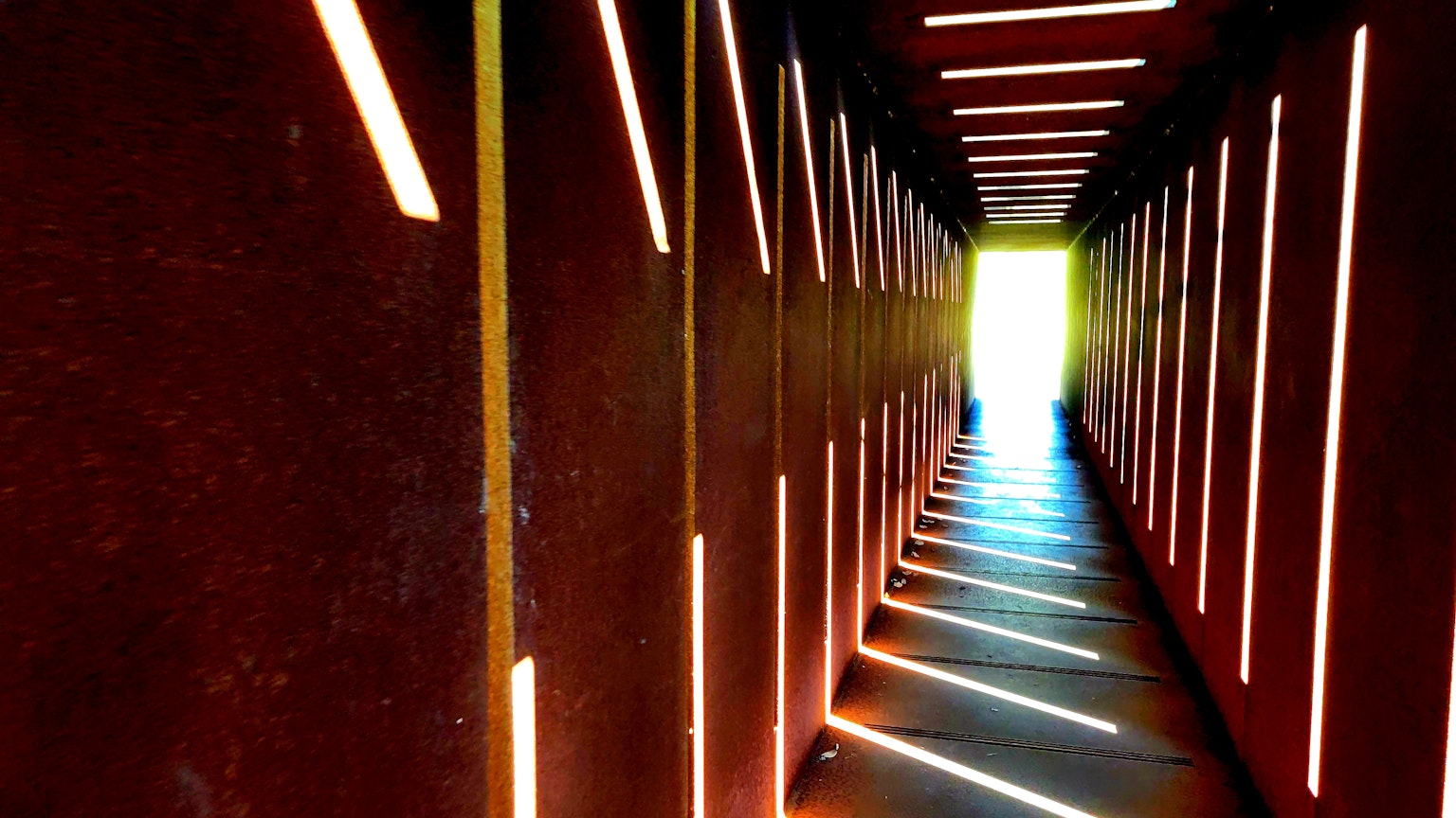 Long couloir avec des murs rouges et des fentes de lumière