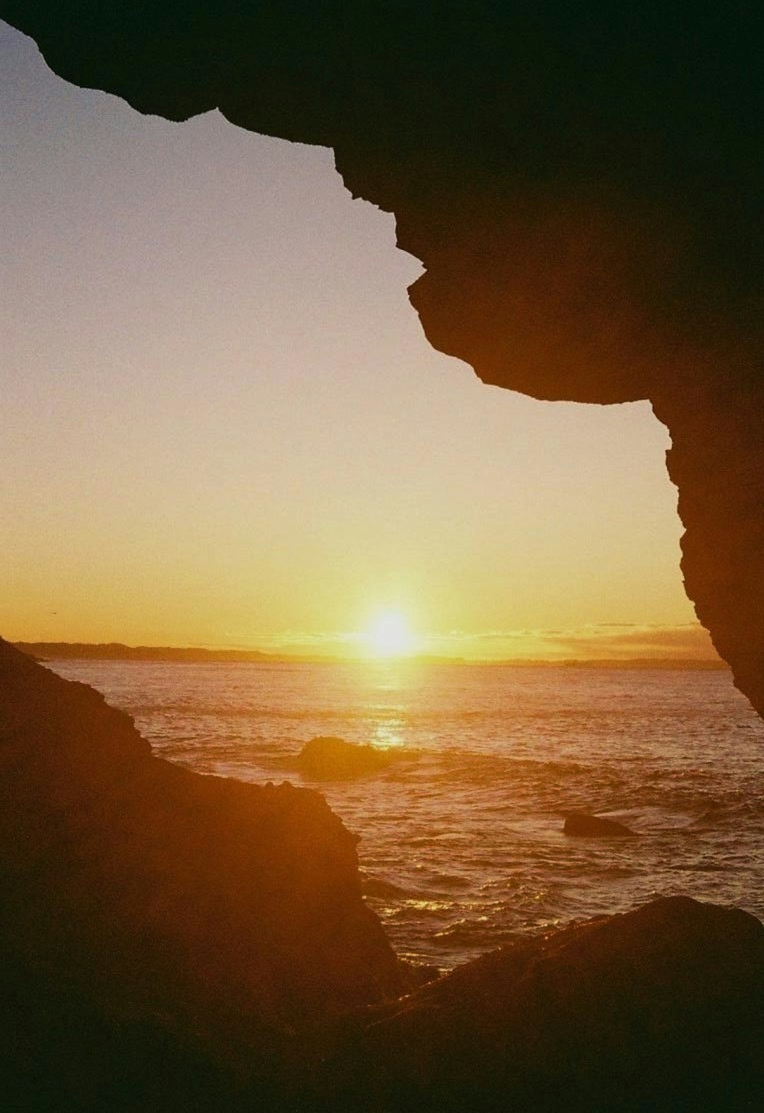 พระอาทิตย์ตกผ่านช่องหินกับคลื่นทะเล