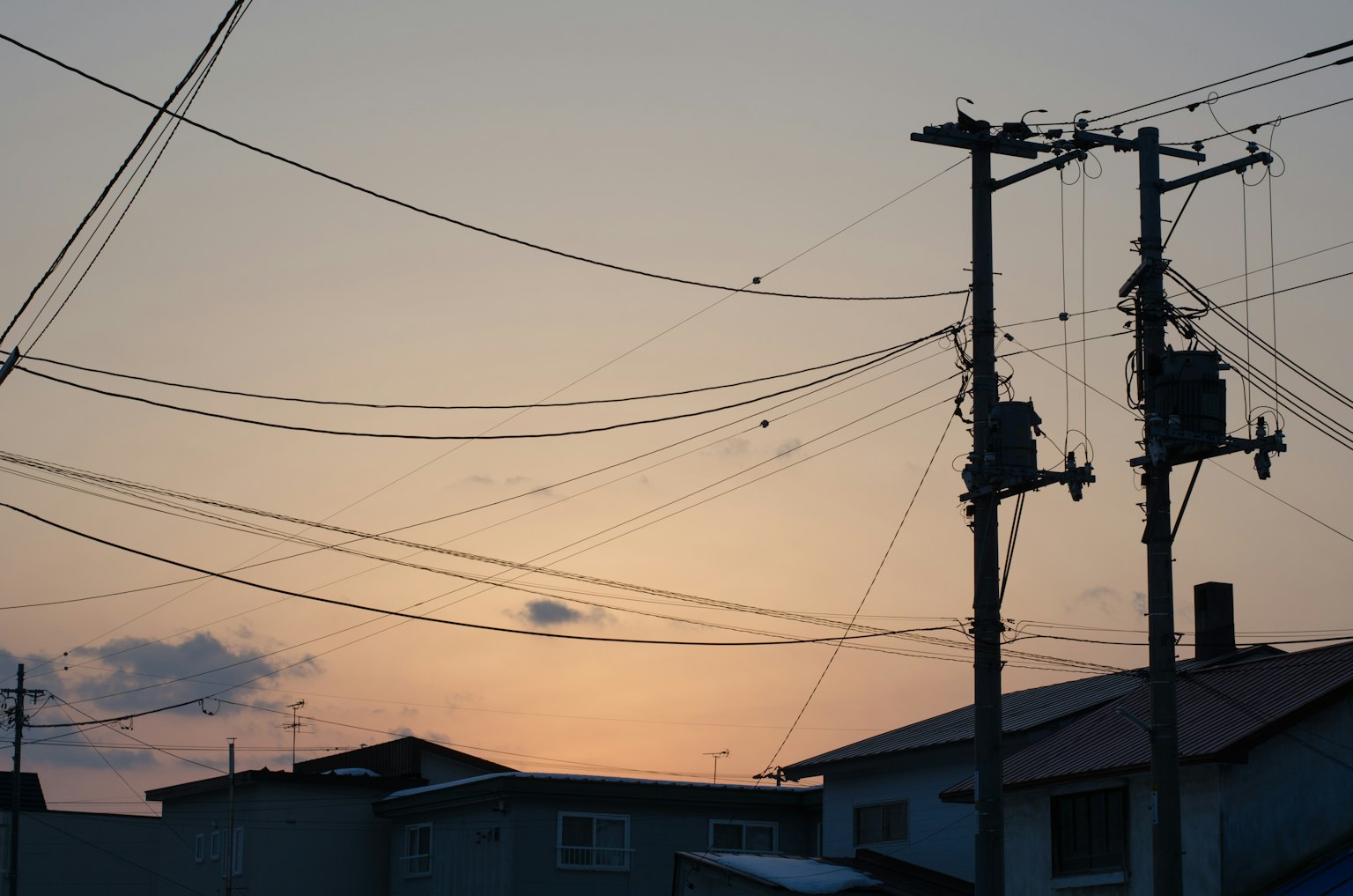 Silhouette de poteaux électriques et de fils contre un ciel au coucher du soleil