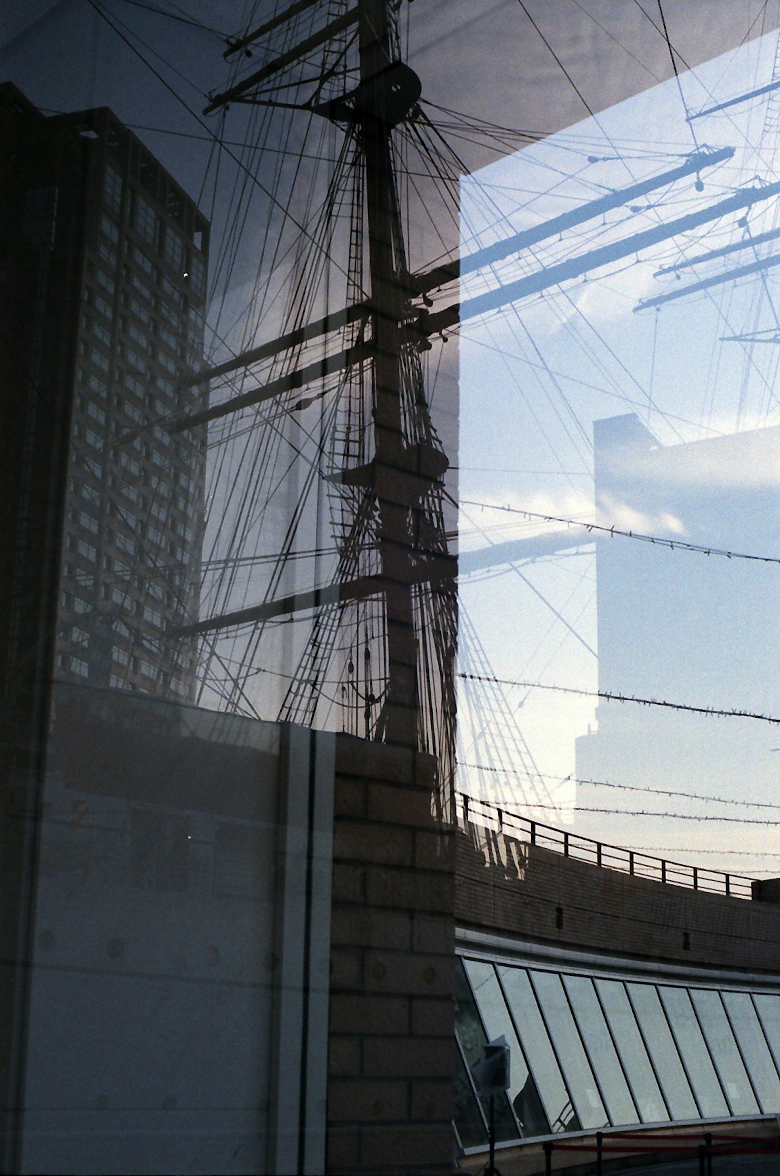 Imagen que refleja un edificio y el mástil de un barco de vela