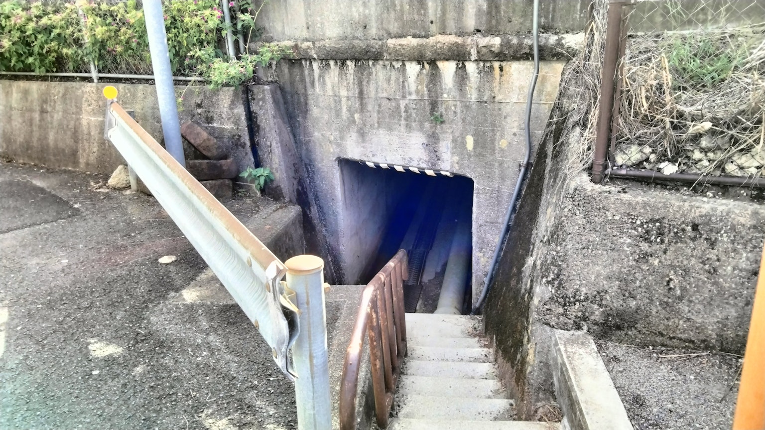 Entrada a un túnel oscuro con escaleras que bajan y paredes de concreto