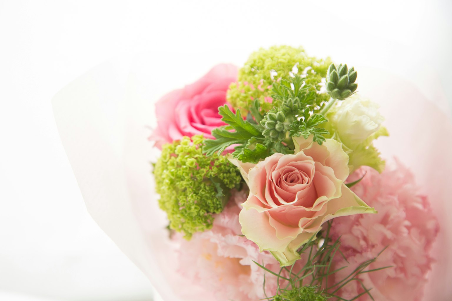 一束包含粉色玫瑰和绿色花朵的花束