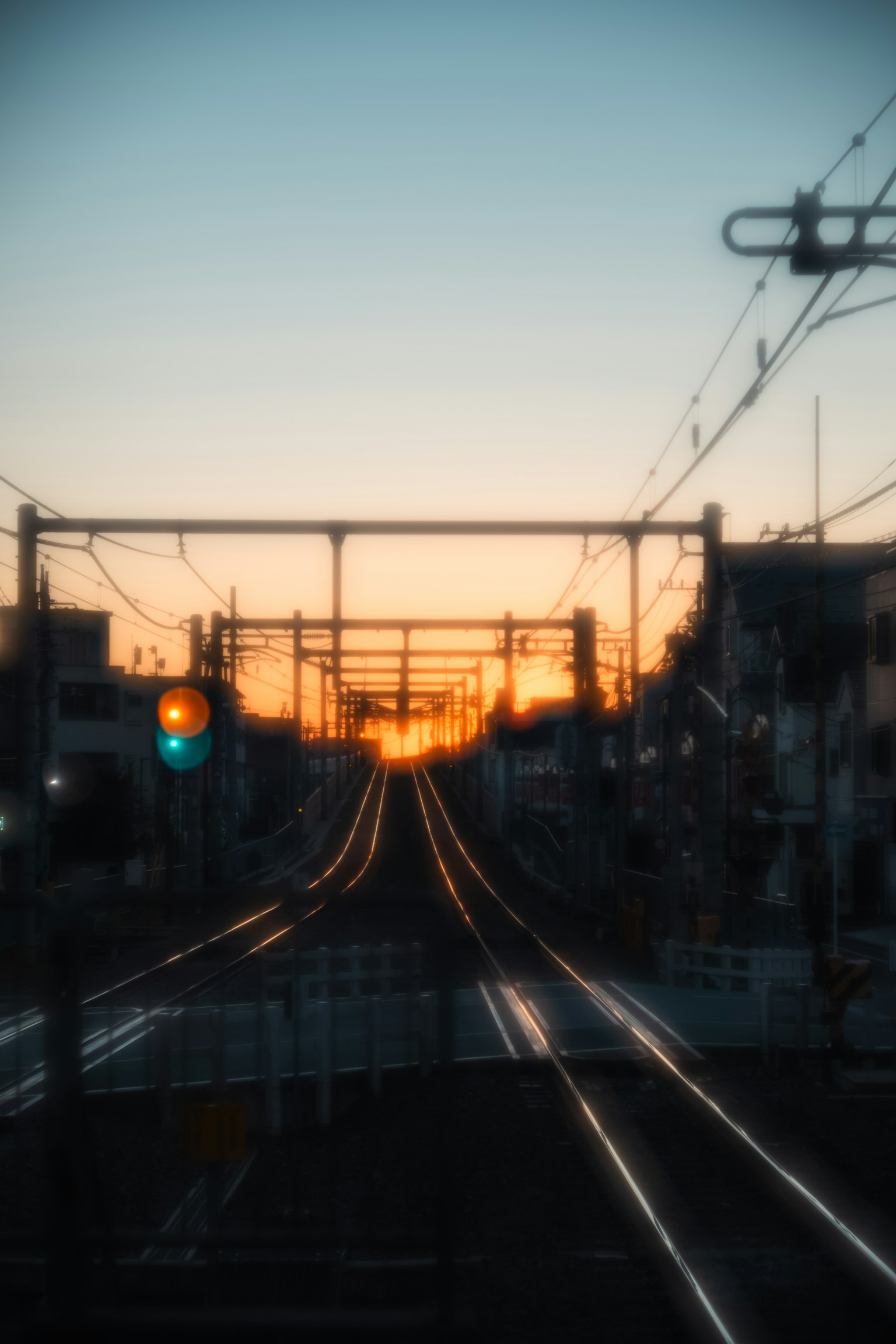 Vista di un tramonto con binari ferroviari e semaforo