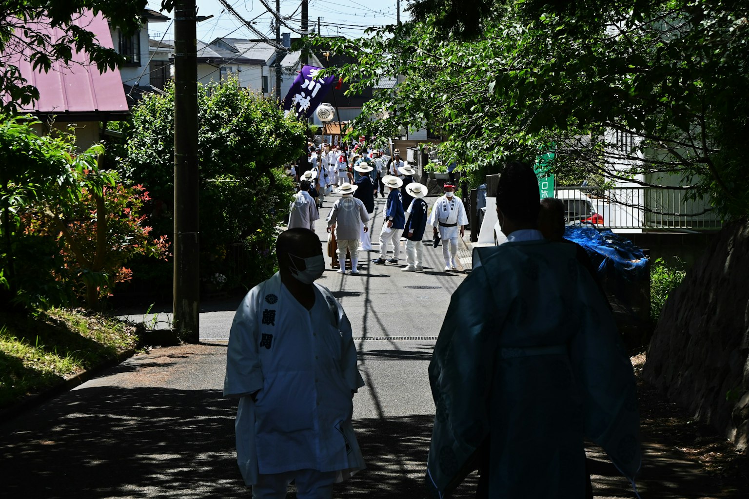People in white clothing walking down a path surrounded by greenery