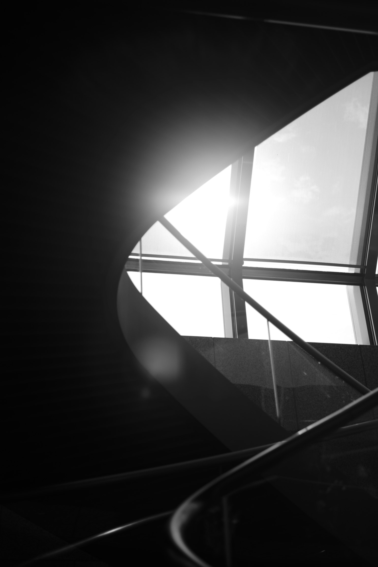 Image en noir et blanc d'un escalier avec de la lumière passant par une fenêtre