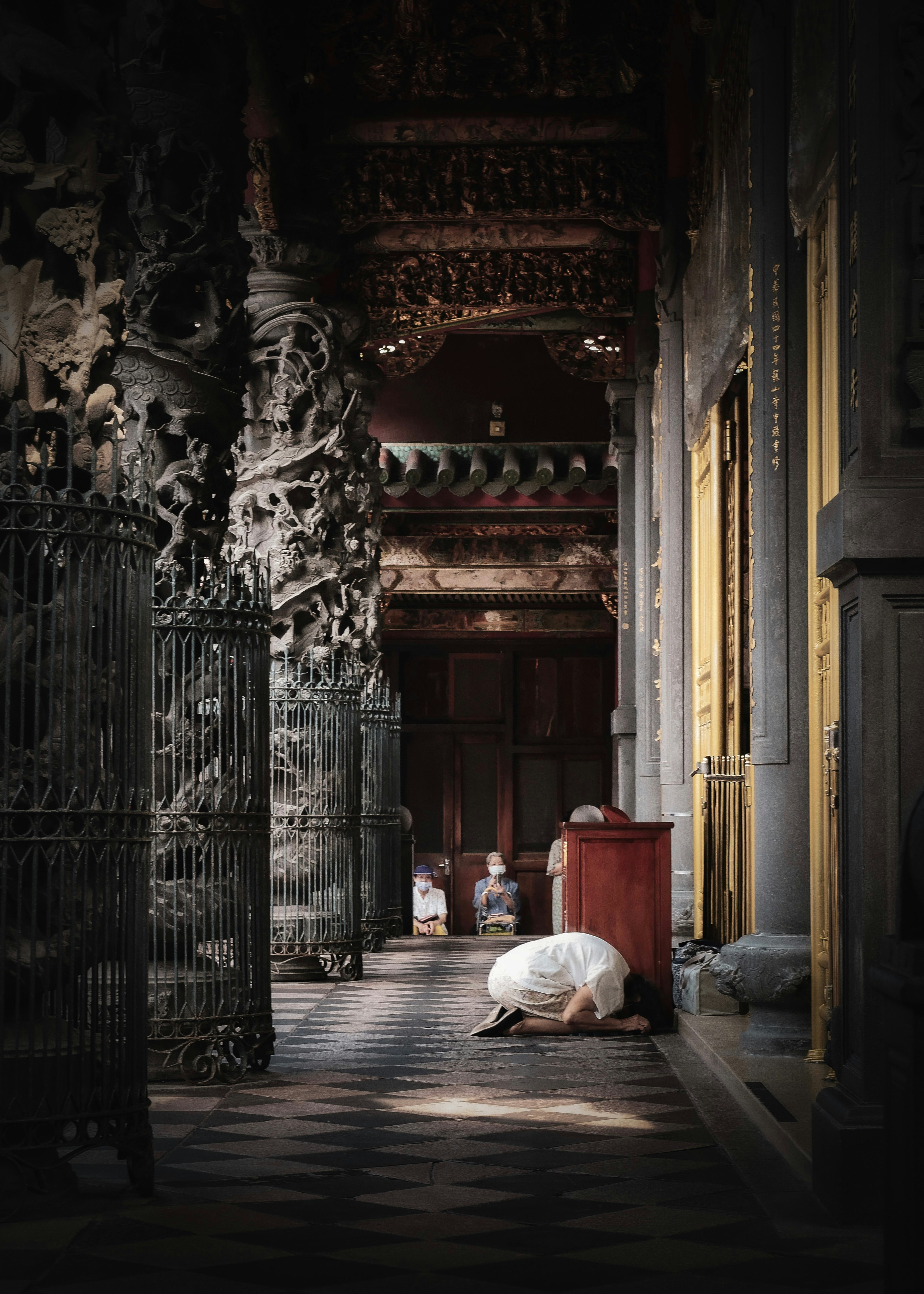 dim temple corridor in Taipei with a person praying