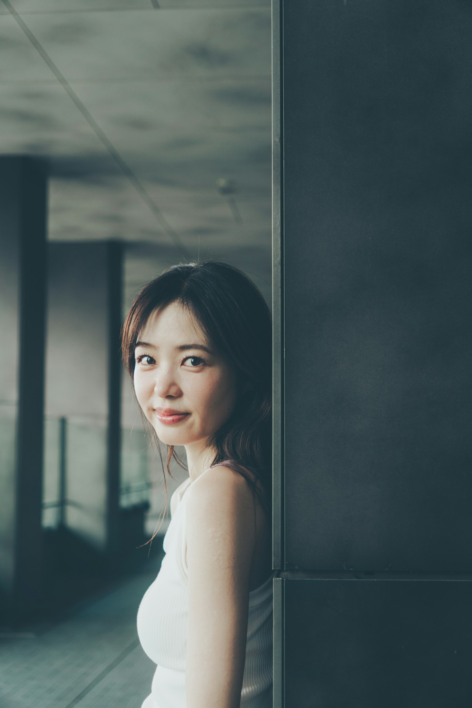 Une femme souriante près d'un mur avec des éléments architecturaux modernes en arrière-plan
