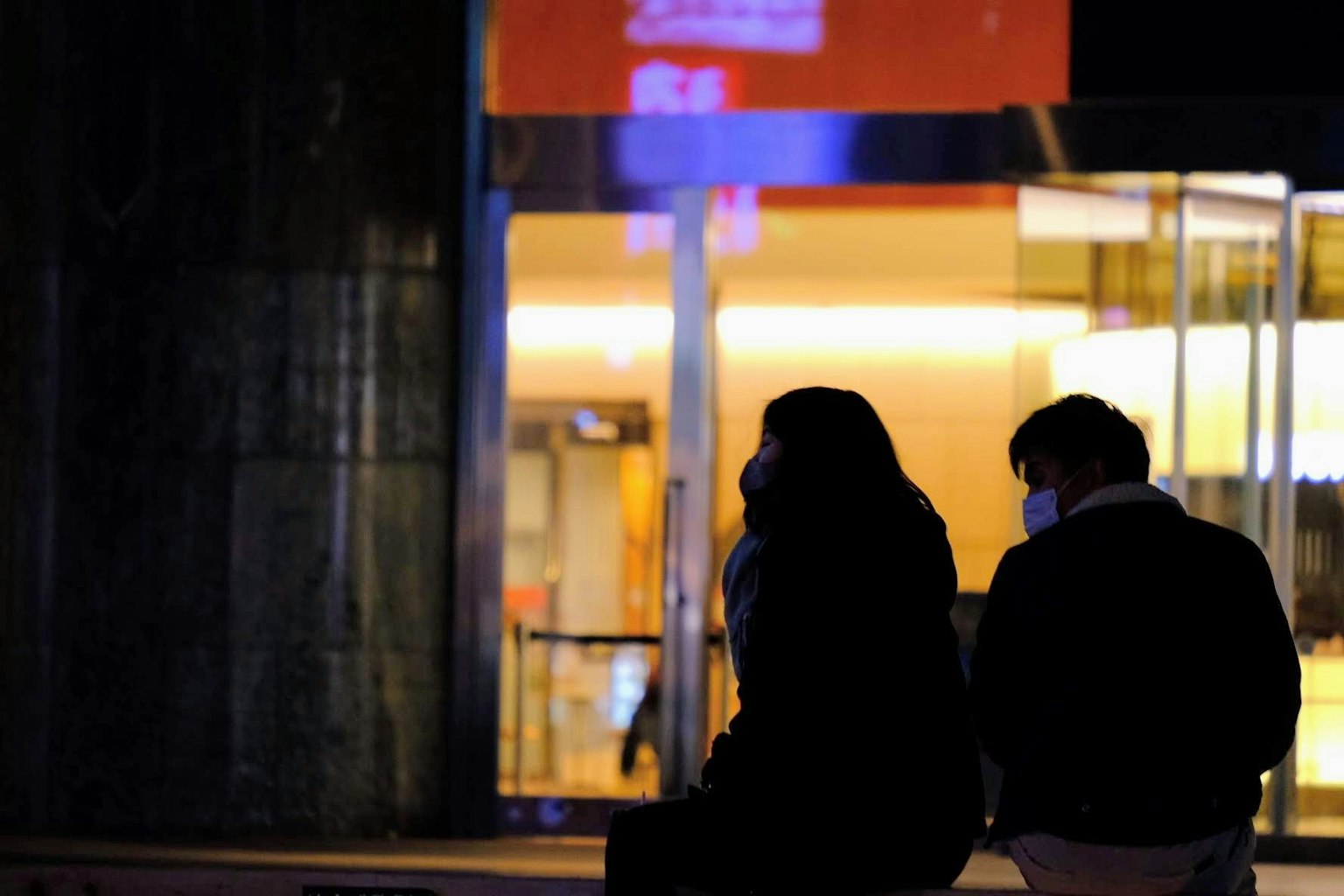 Silhouette d'un couple assis devant un magasin élégant la nuit
