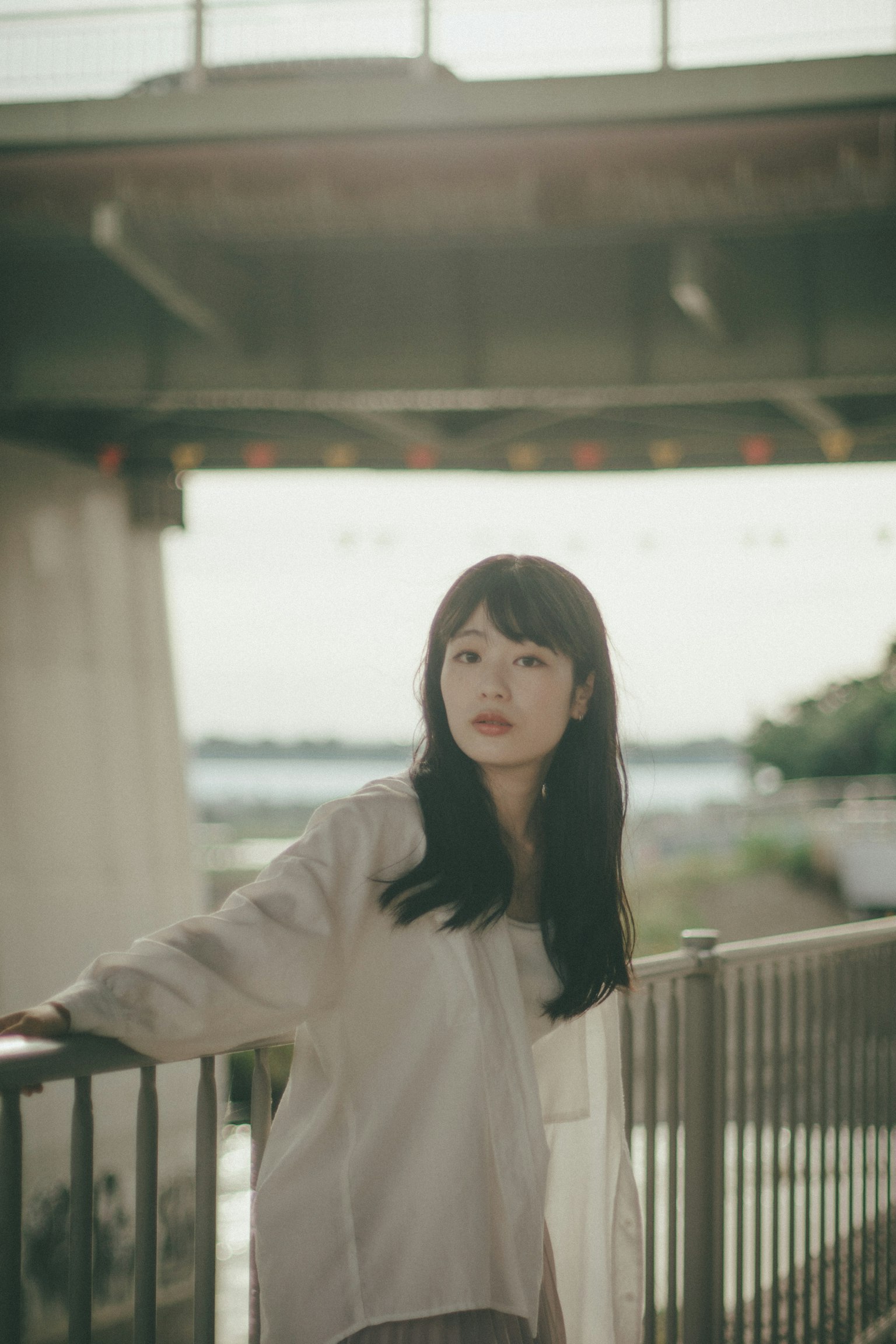 一位女性在橋下擺姿勢 背景是寧靜的水和綠地
