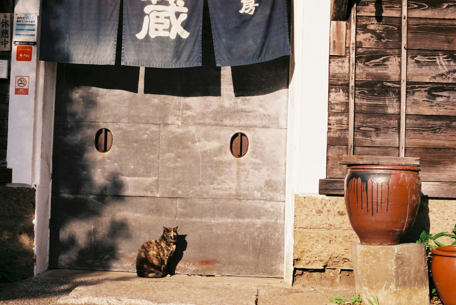 Eine Katze sitzt vor einem traditionellen Holzhaus mit Schiebetür