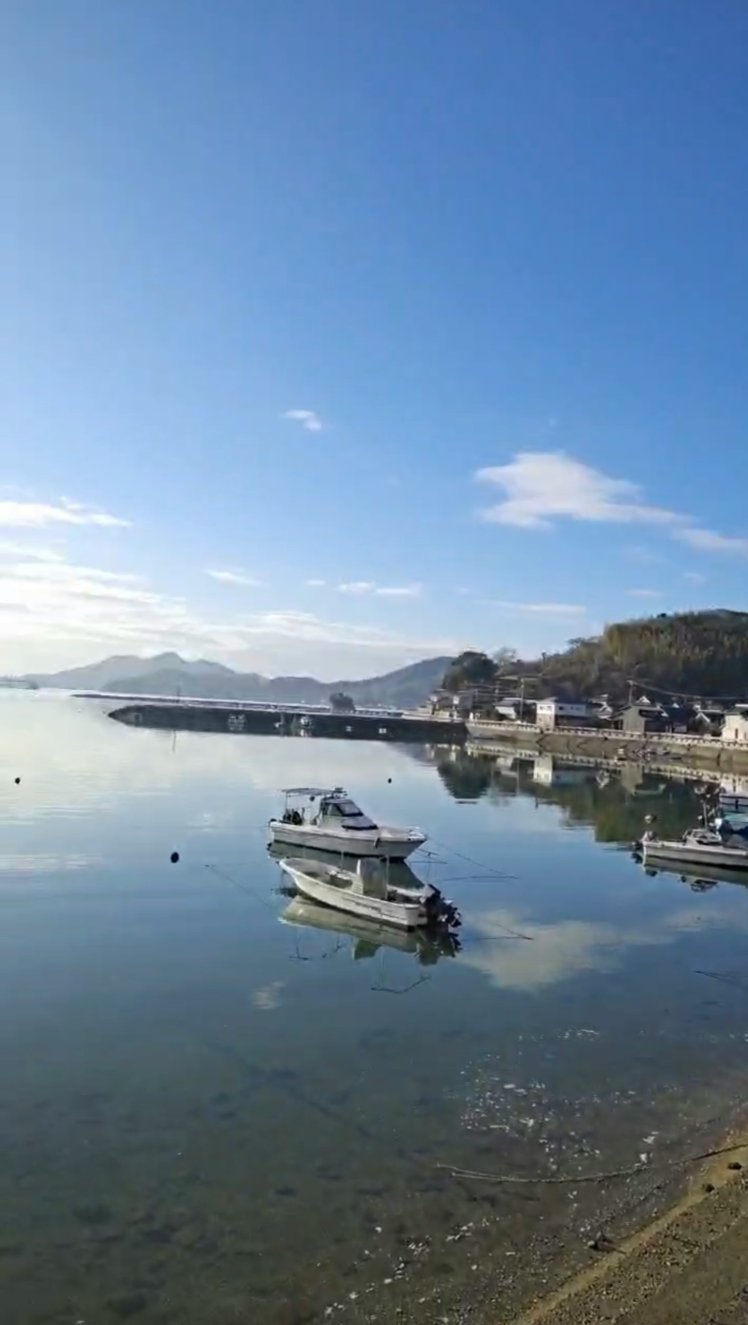 A serene view of a boat floating in a calm harbor with a reflective water surface