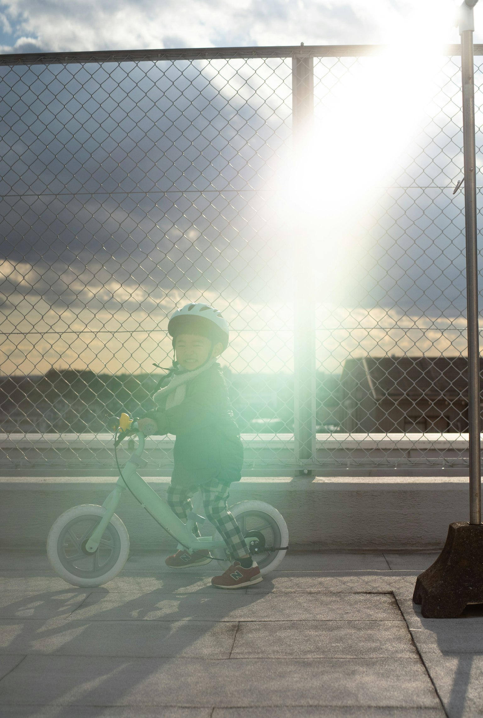 Niño montando una bicicleta de equilibrio con destello de sol al atardecer