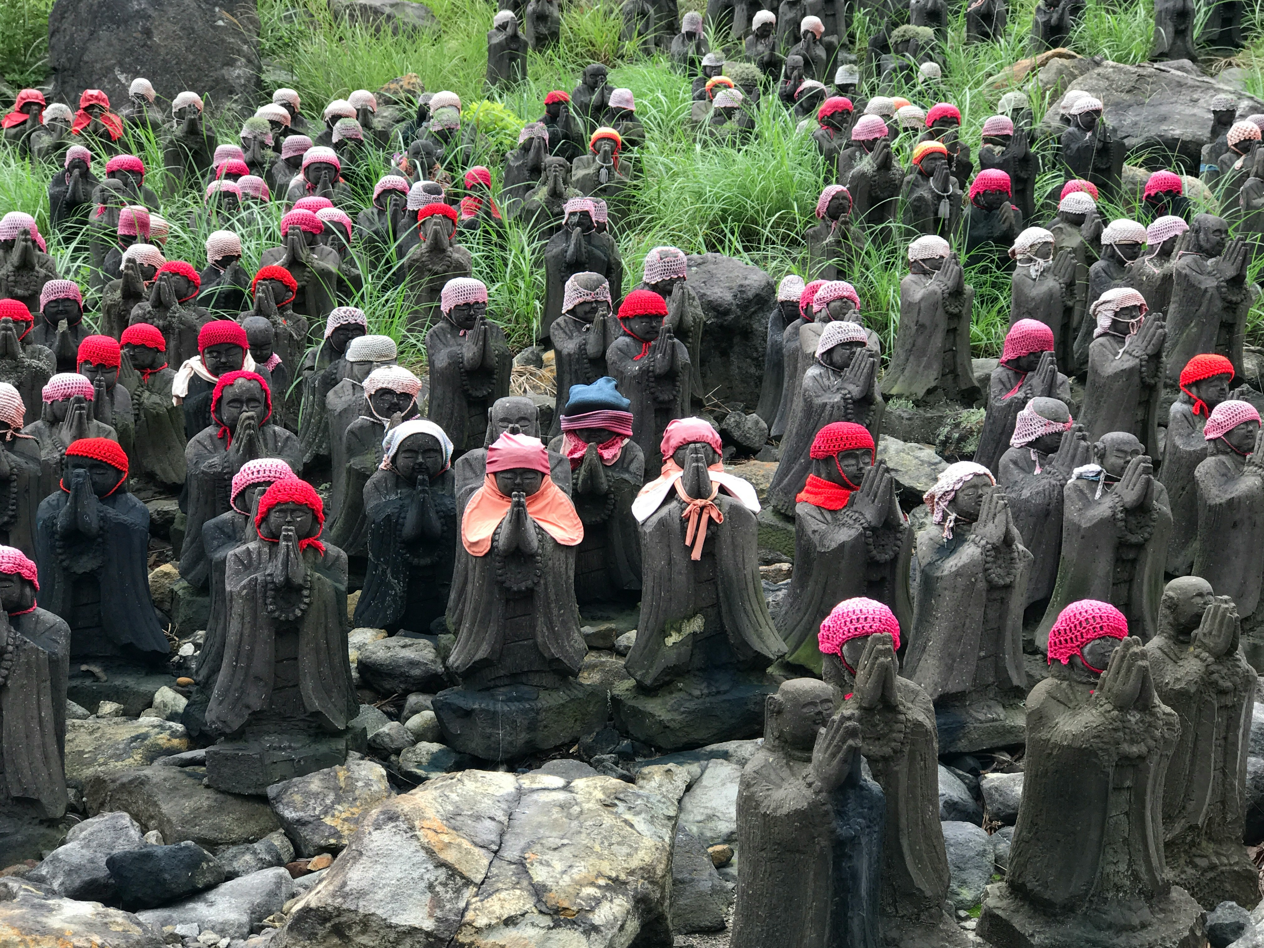 groupe de statues en pierre de personnages à capuchons rouges en extérieur