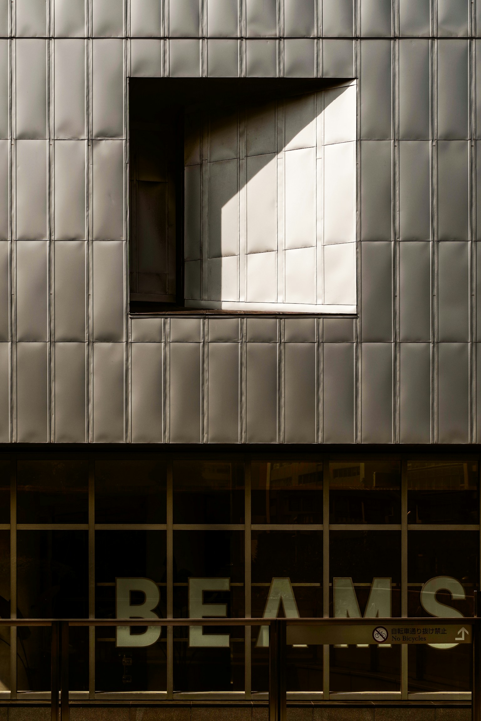 Façade de bâtiment moderne avec une forme de fenêtre unique et un reflet de lumière avec le mot BEAMS