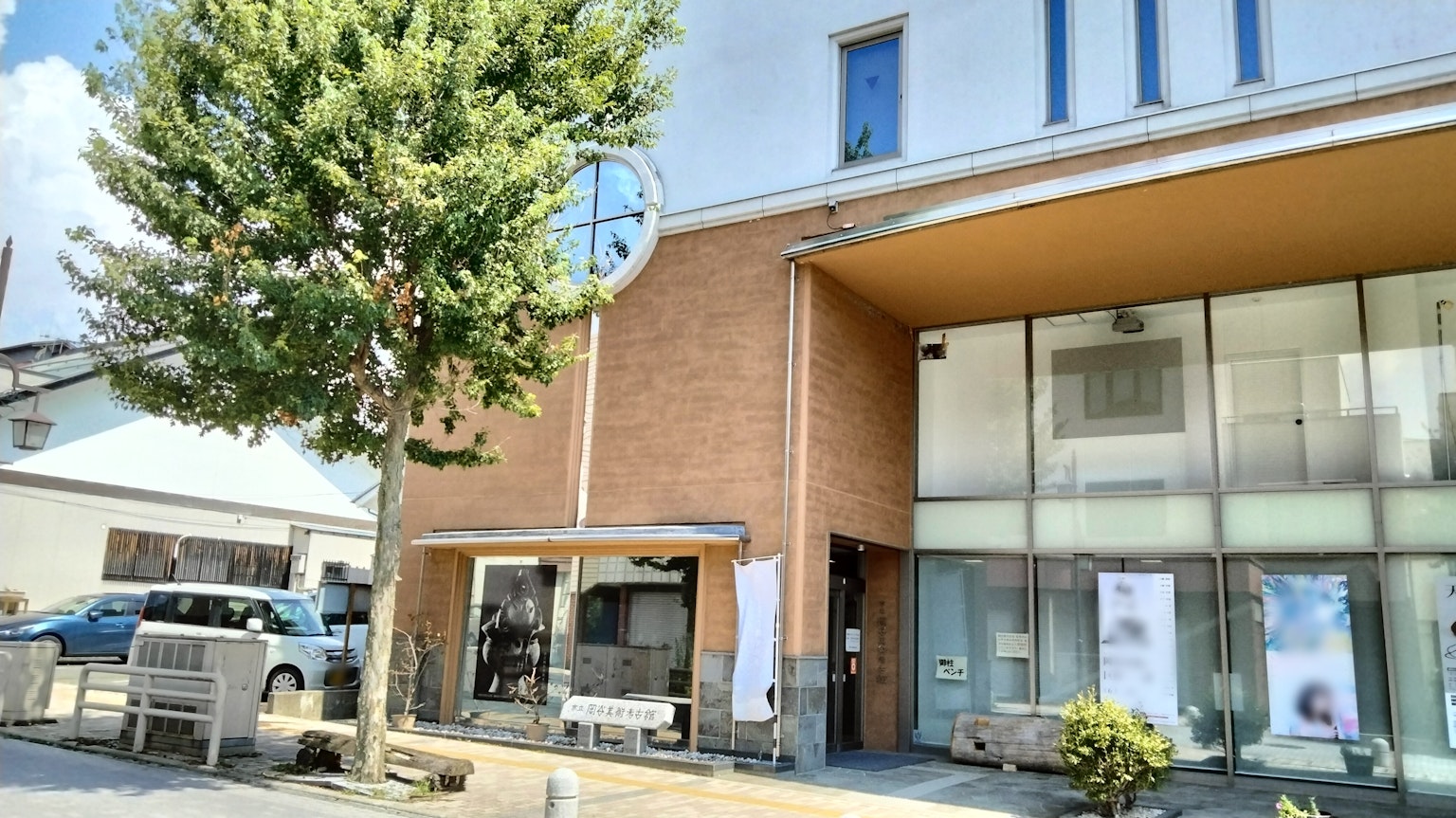 Bâtiment moderne avec de grandes fenêtres et un arbre vert sous un soleil éclatant