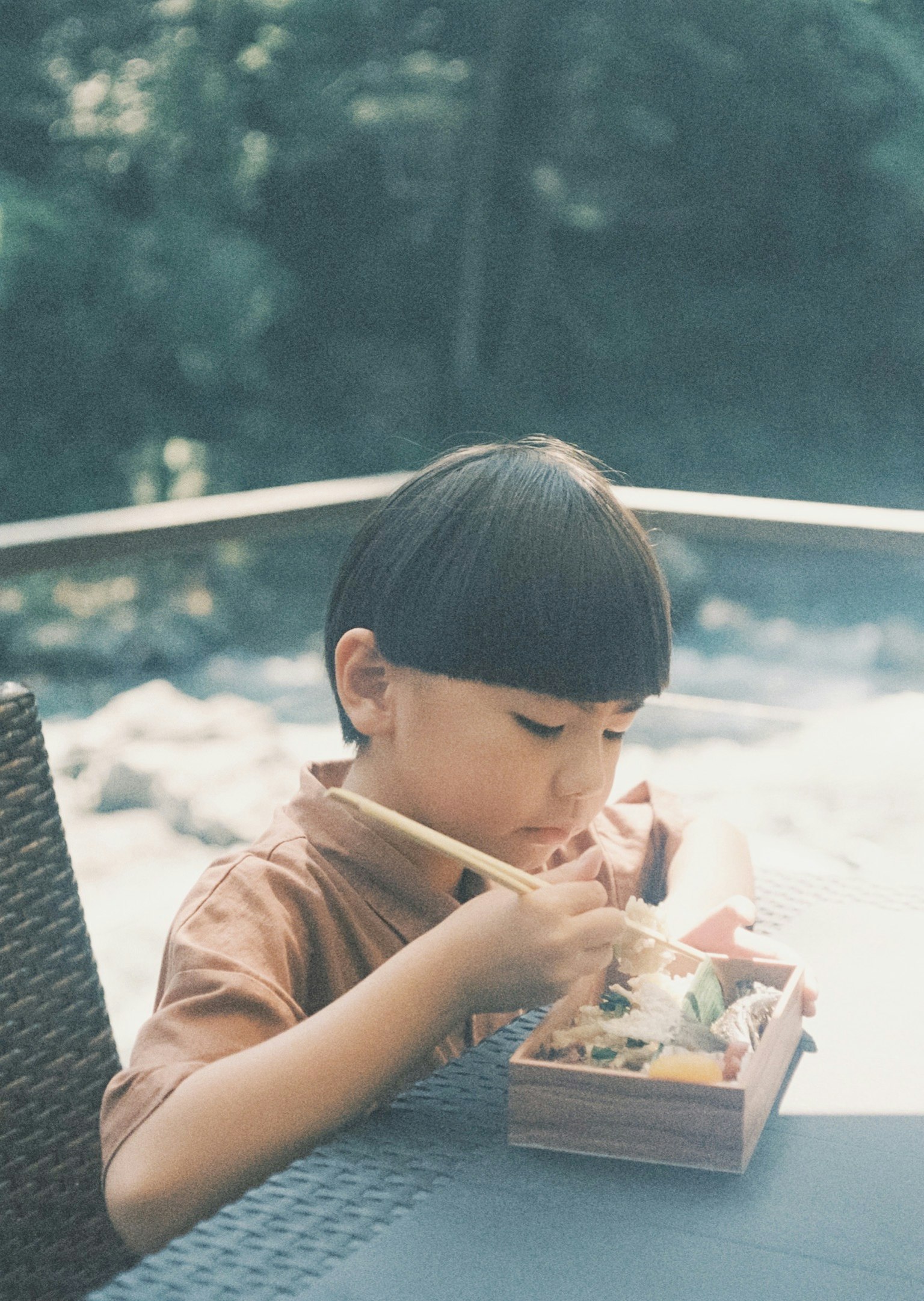 Un bambino che gusta una scatola bento in un ambiente naturale