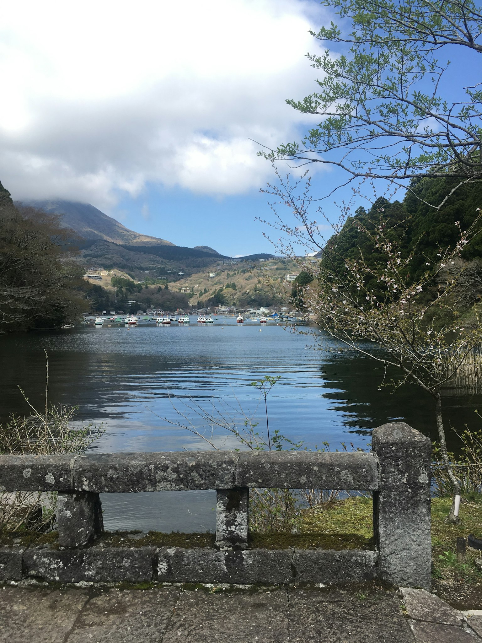 Ruhige Aussicht auf einen See mit Bergen im Hintergrund und einem Steingeländer