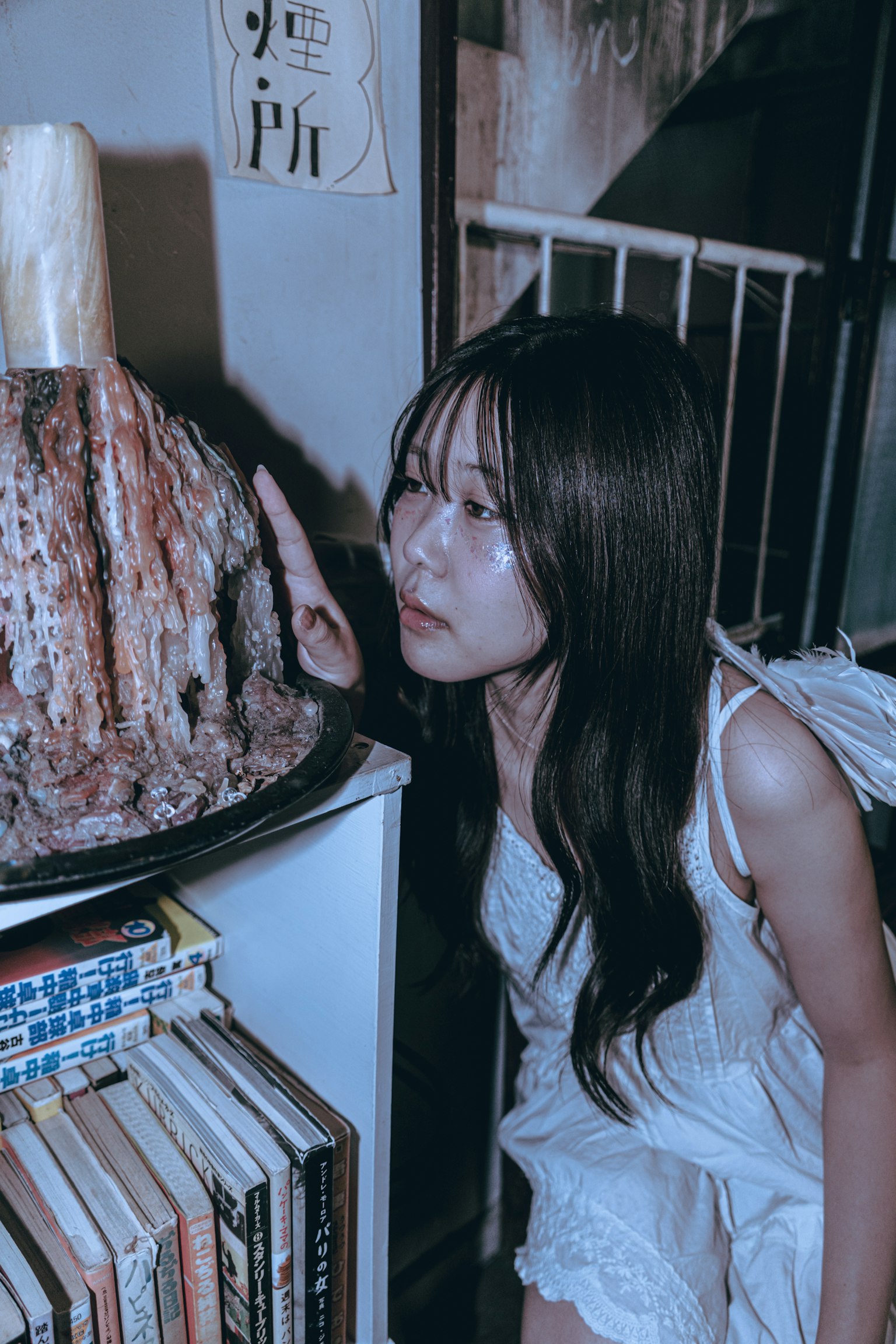 女性が本棚の近くでオブジェを見つめているシーン