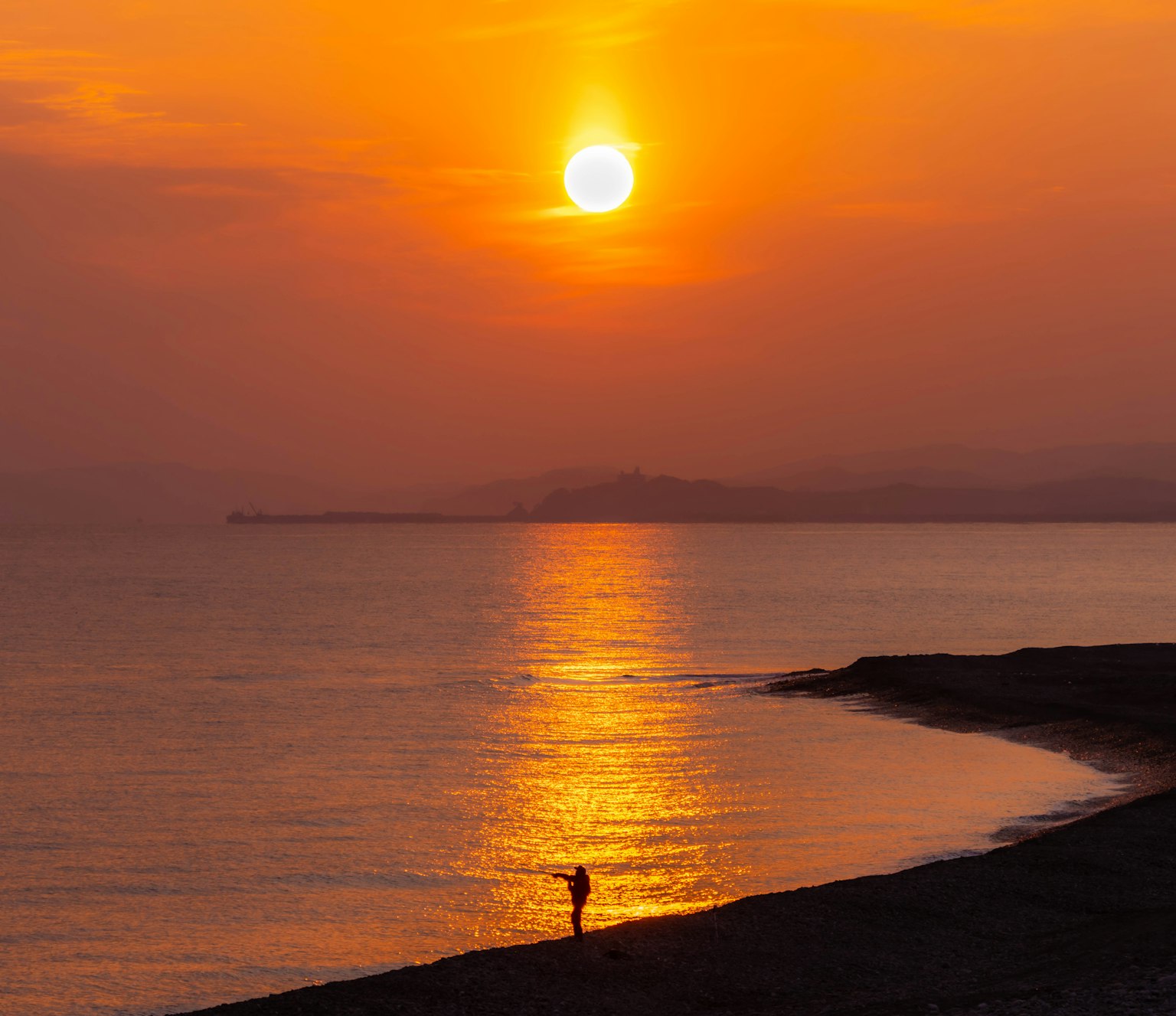 Silhouette einer Person vor einem beeindruckenden Sonnenuntergang über dem Ozean