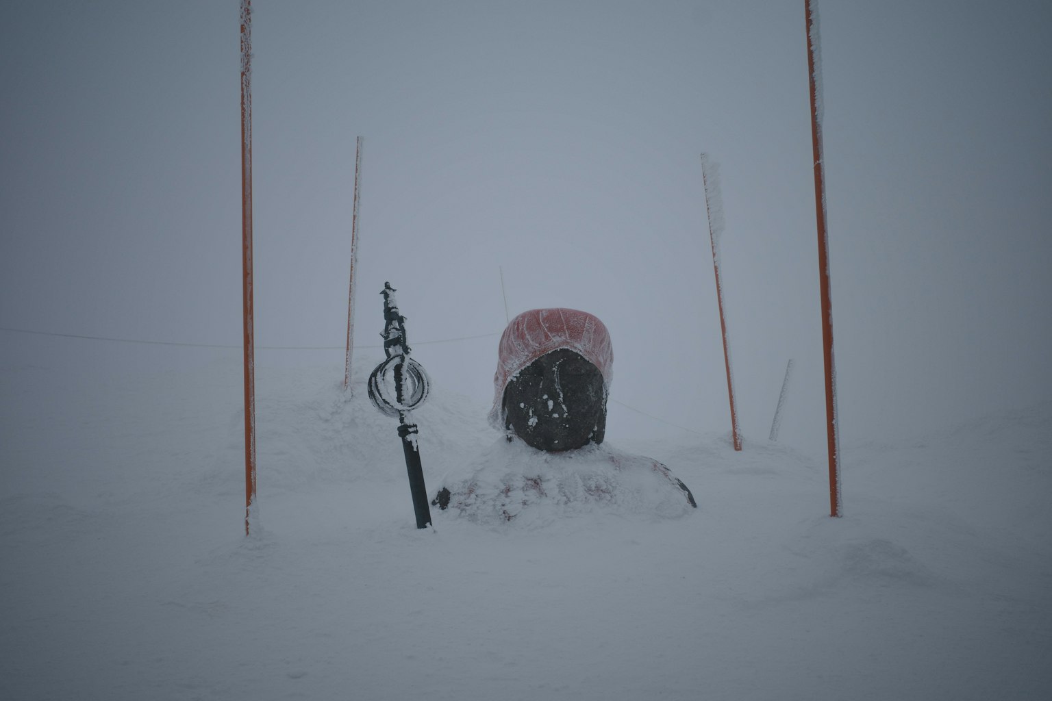 Mit Schnee bedeckte Skiausrüstung mit roten Pfählen in einer Winterlandschaft