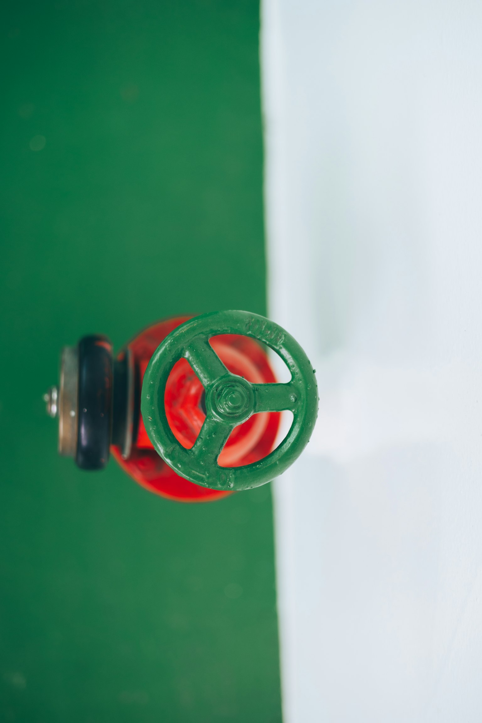 Top view of a fire hydrant featuring a red valve and green handle
